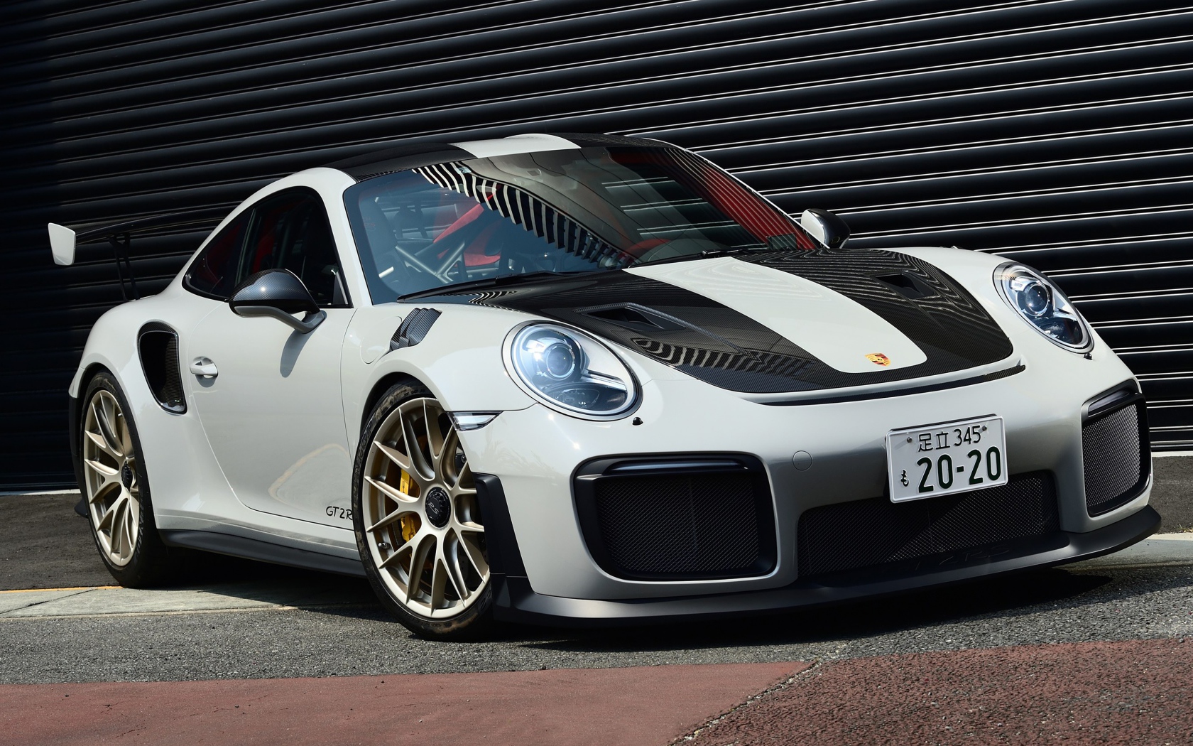 Белый автомобиль Porsche 911 GT2 RS  у черной стены