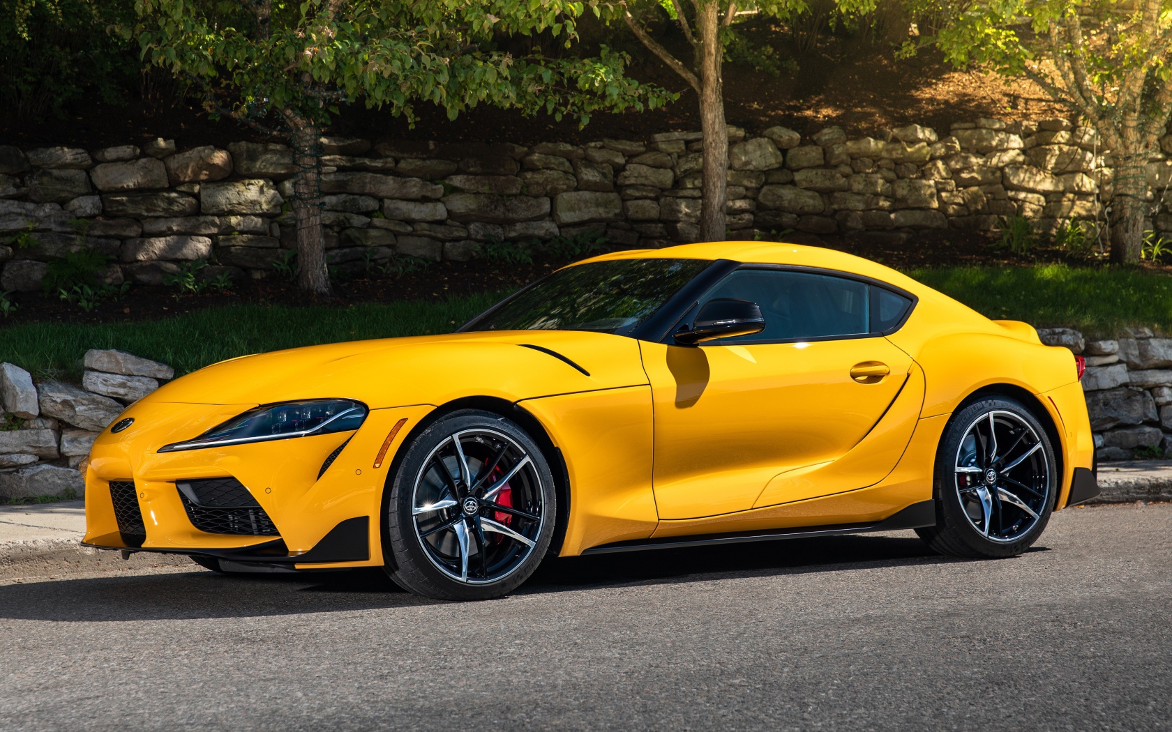 Желтый автомобиль Toyota GR Supra,ю 2021 года у стены