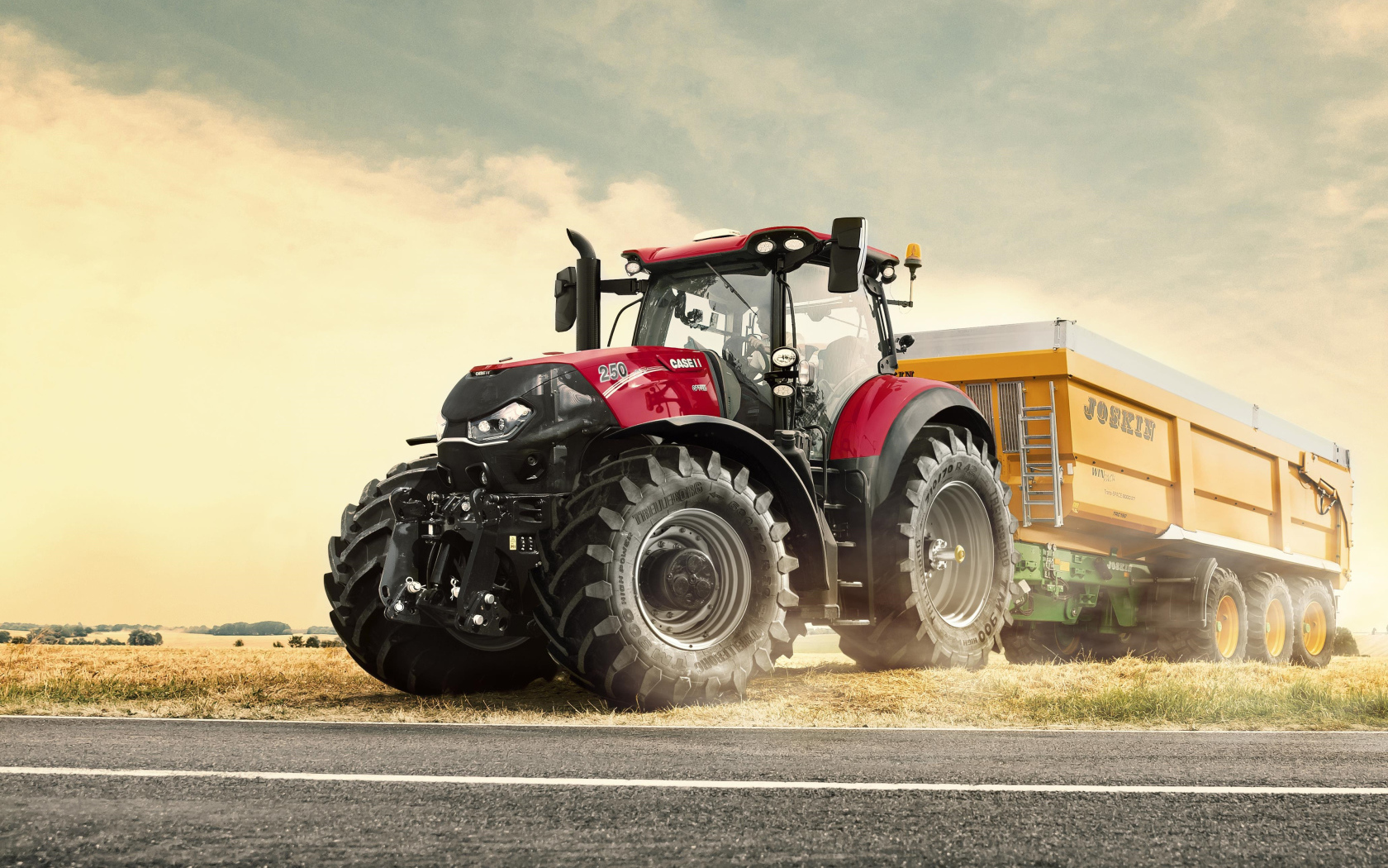 Большой красный трактор с прицепом в поле