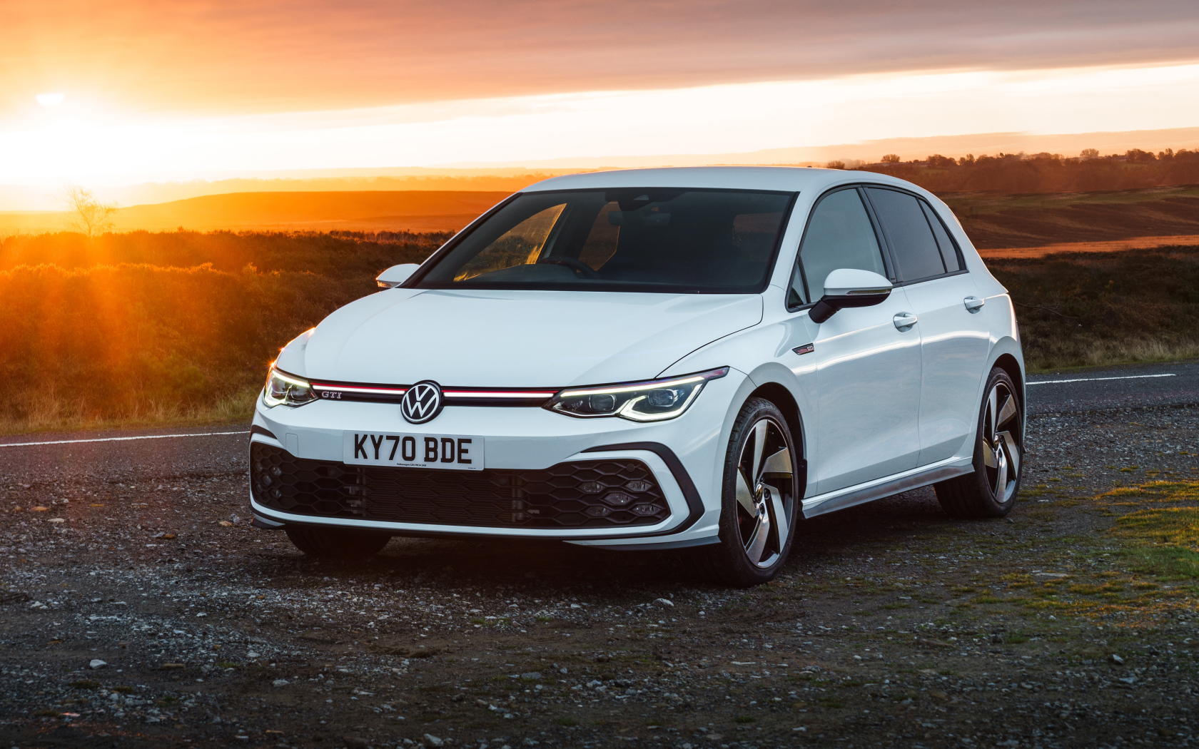 Белый автомобиль Volkswagen Golf GTI 2020 года на закате солнца