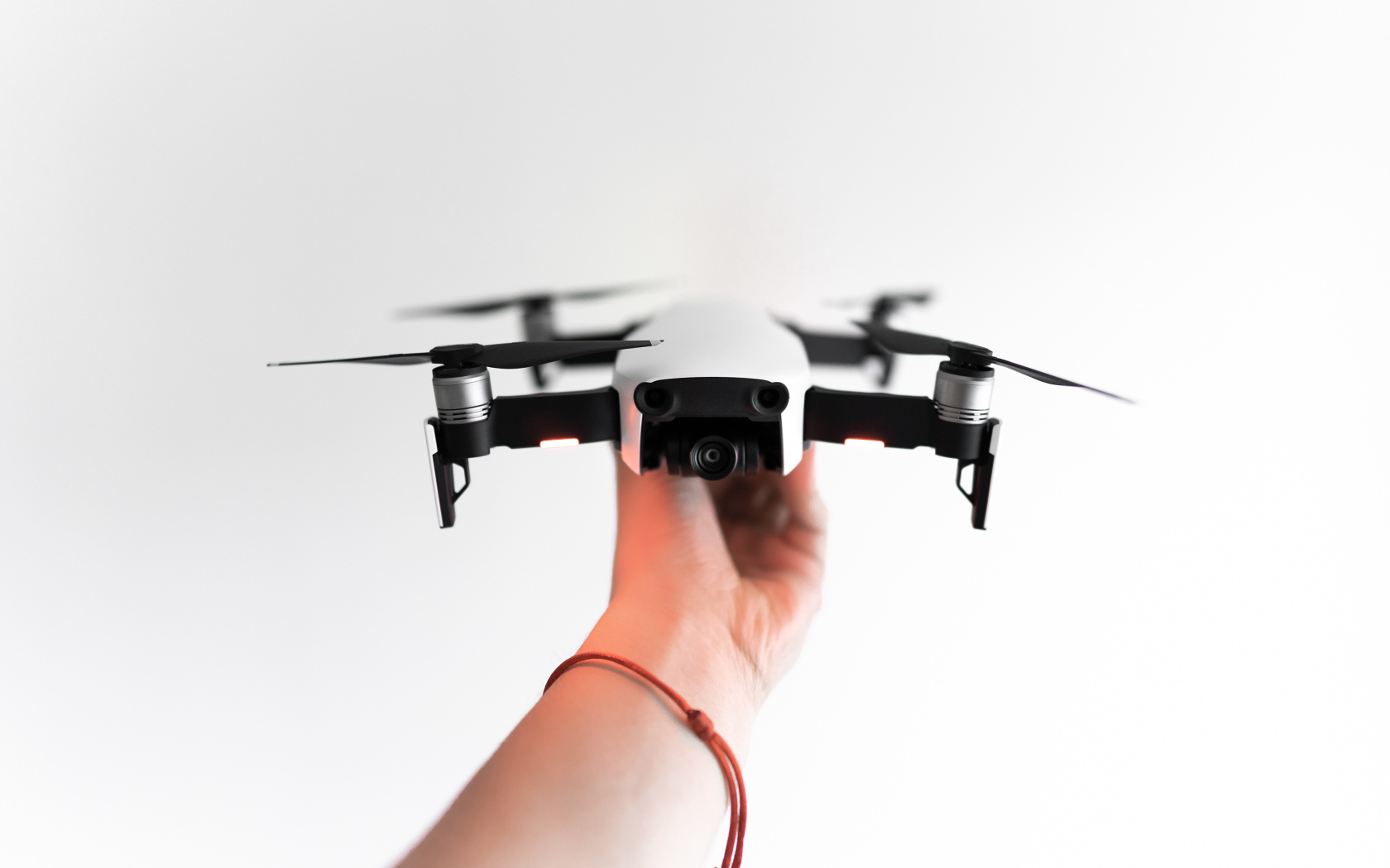 Белый квадрокоптер в руке на белом фоне