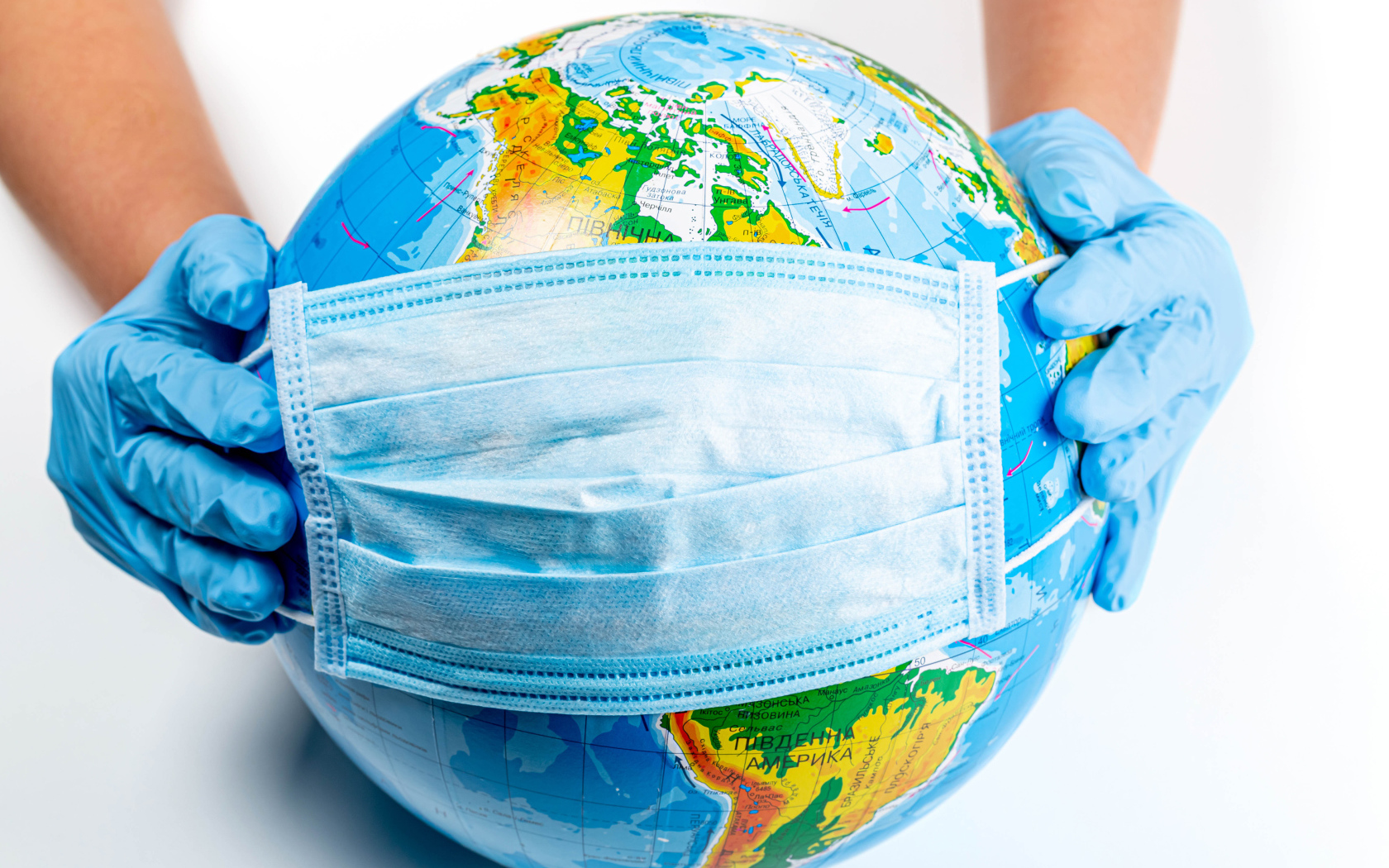 Руки одевают маску от коронавируса на глобус 