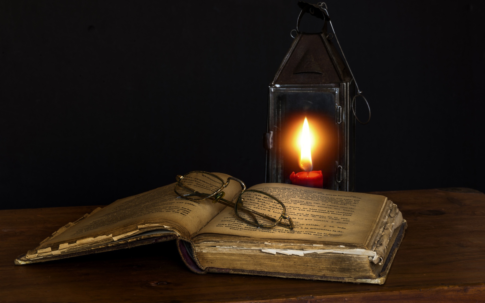Старая книга на столе с очками и лампой