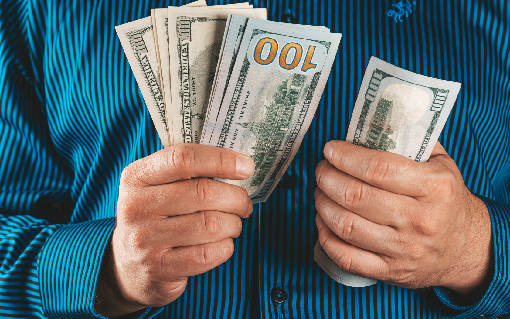 Мужчина считает сто долларовые купюры 