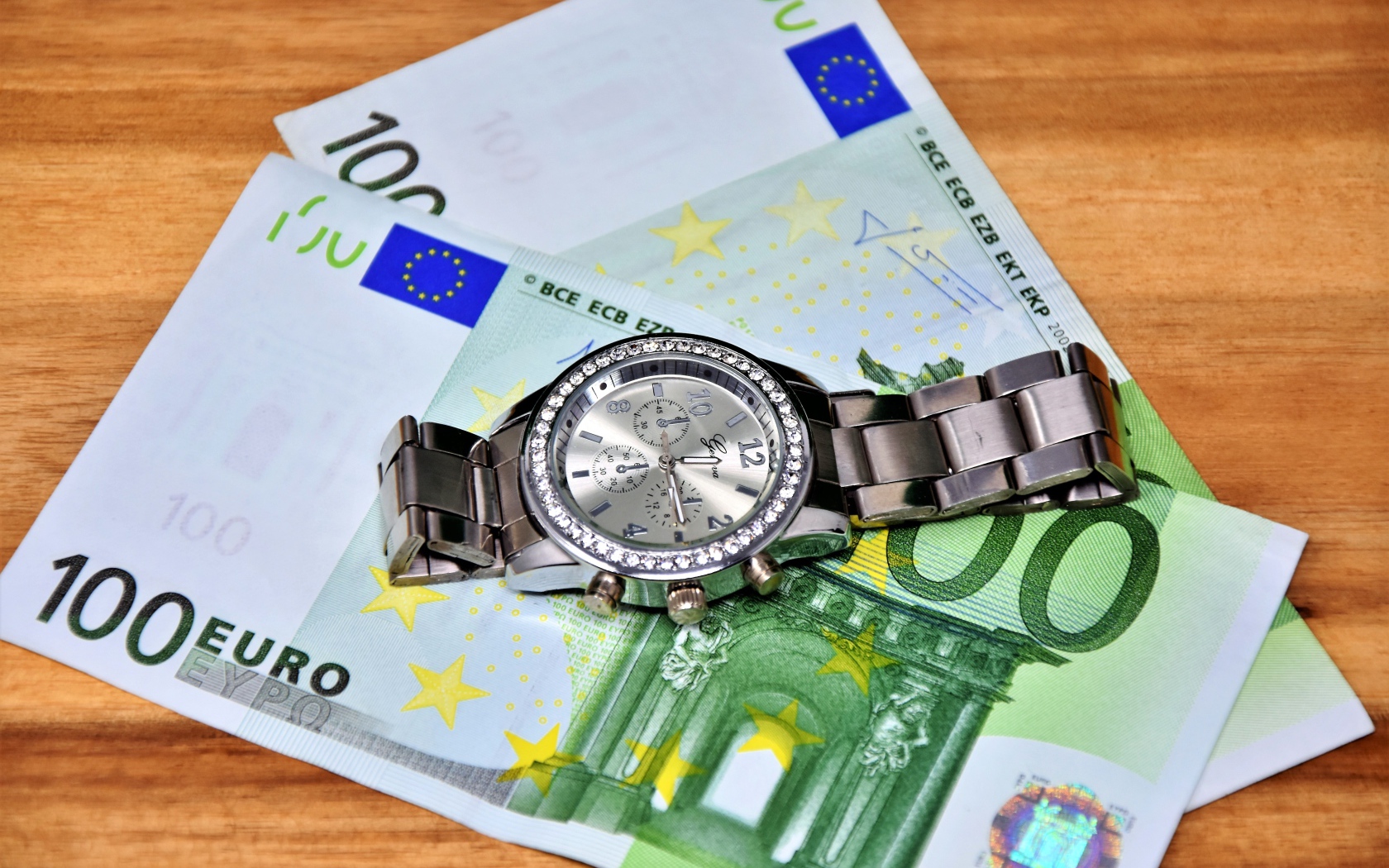 Two hundred euro bills with a clock on the table