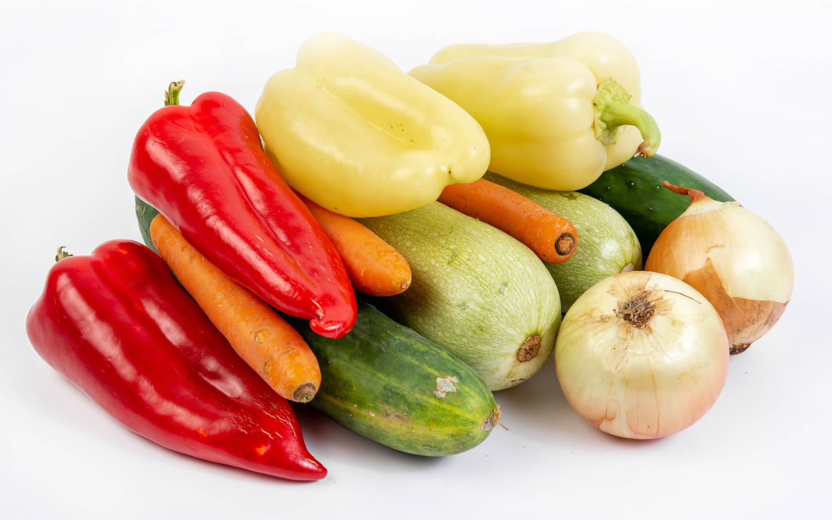 Свежие кабачки, огурцы, морковь, перец и лук на белом фоне