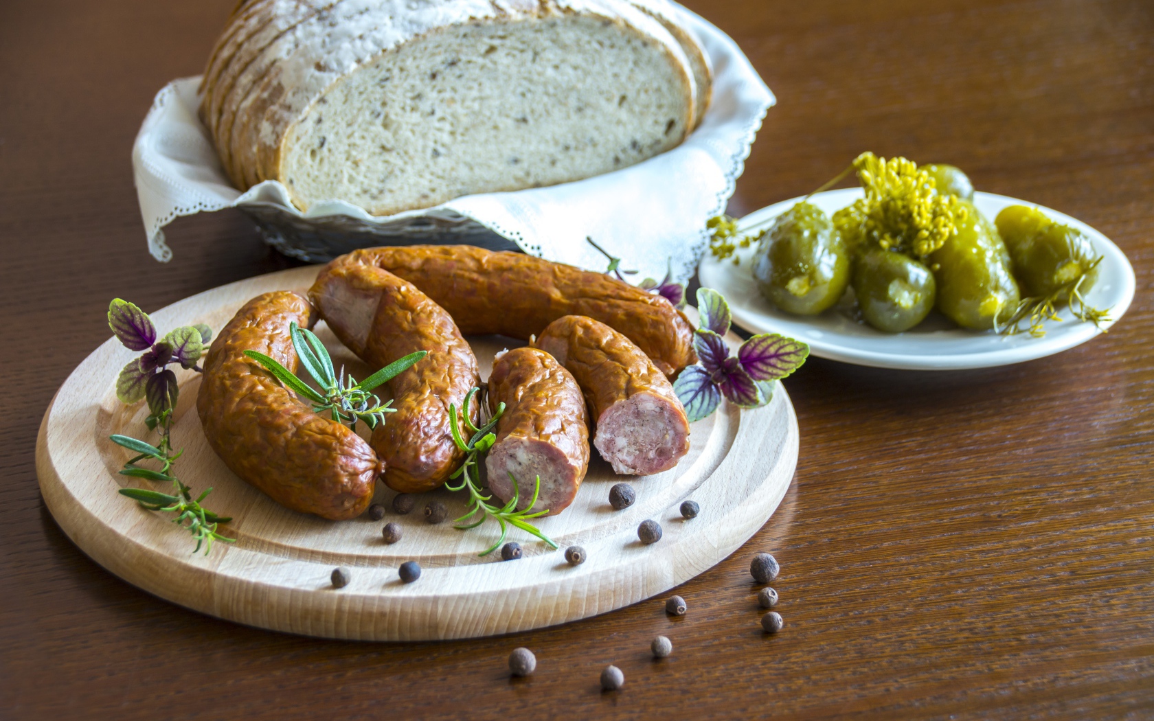 Домашняя колбаса на столе с хлебом и маринованными огурцами