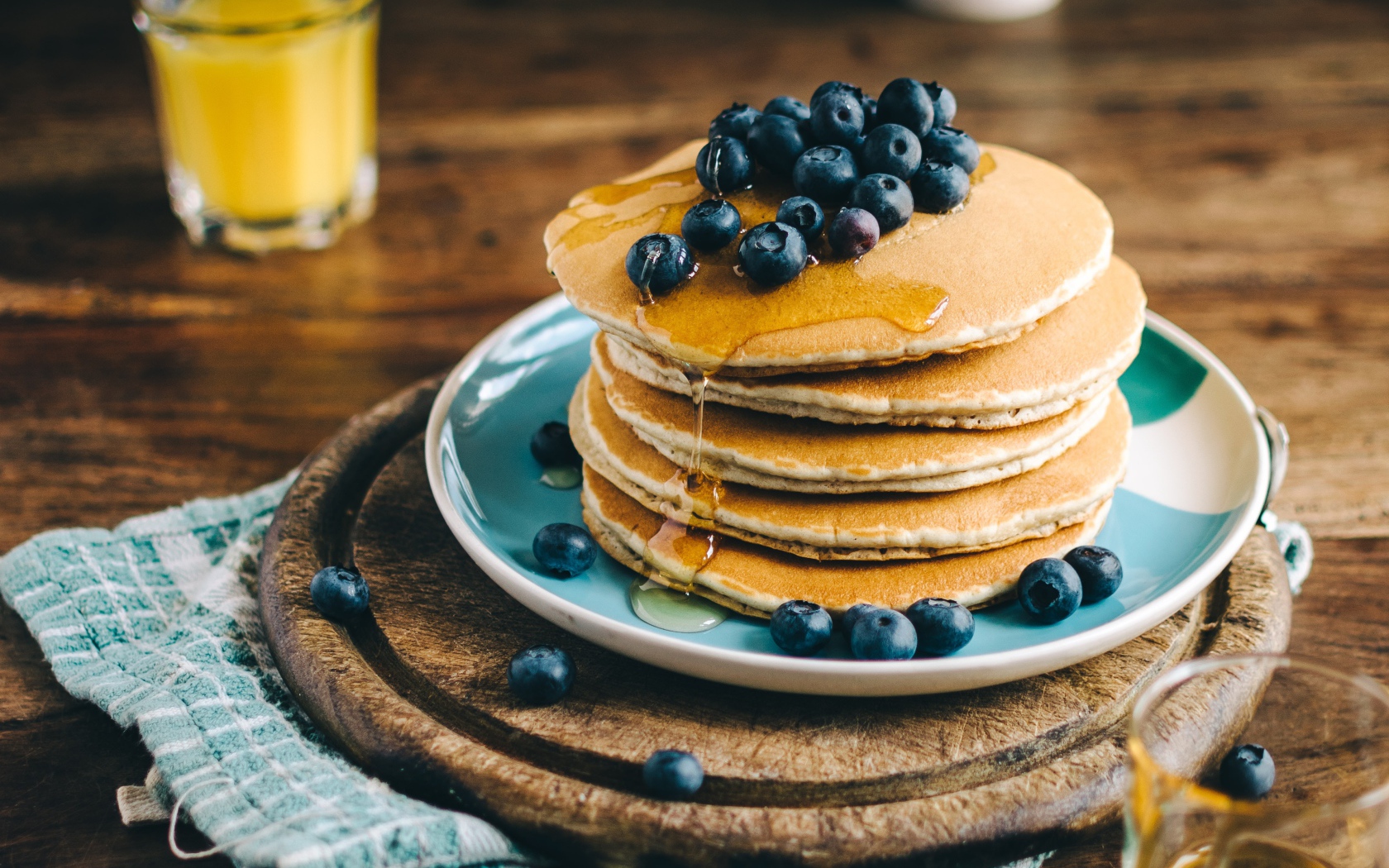 Румяные оладья на тарелке  с медом и ягодами черники 