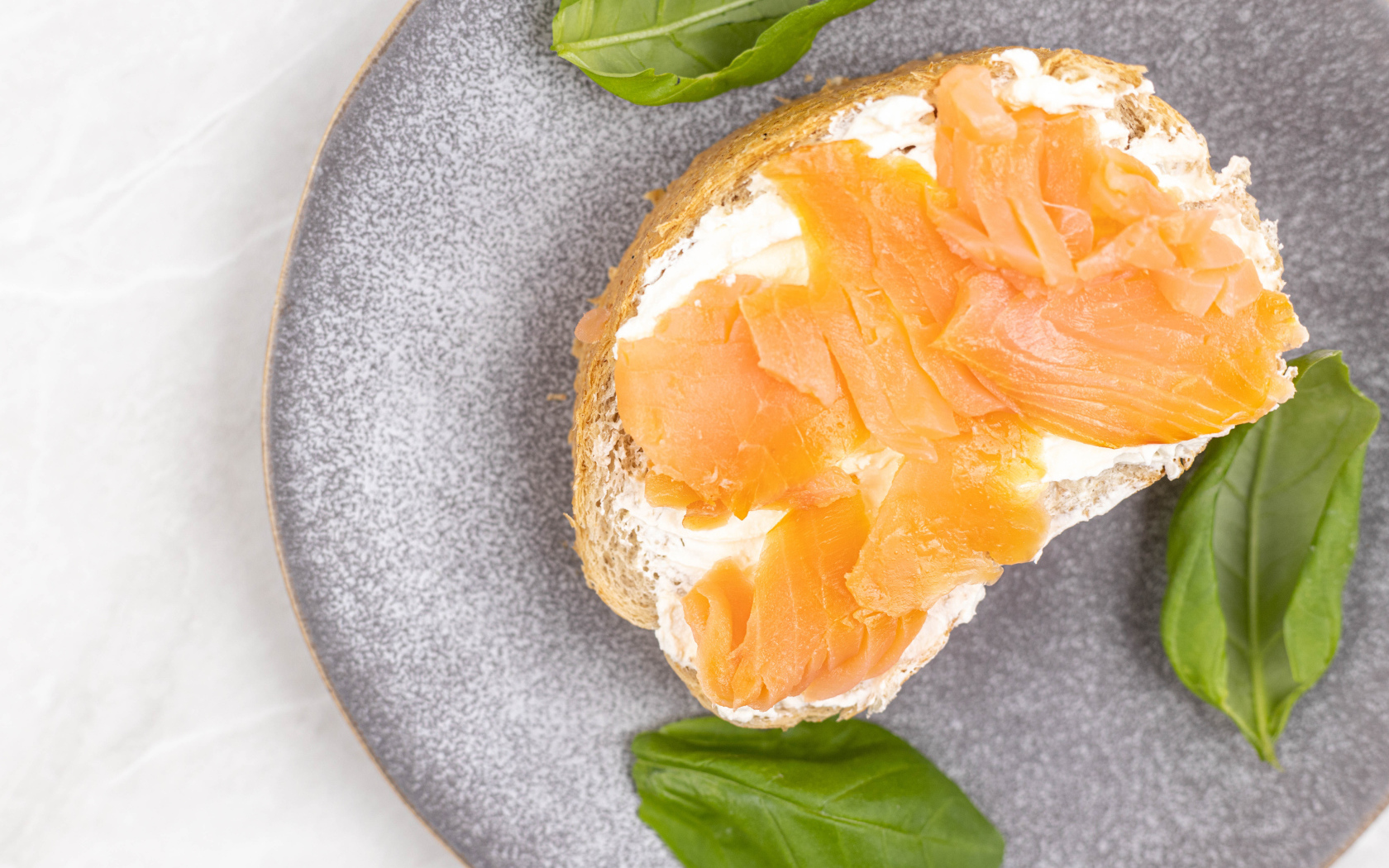 Бутерброд с сыром, красной рыбой и листьями базилика