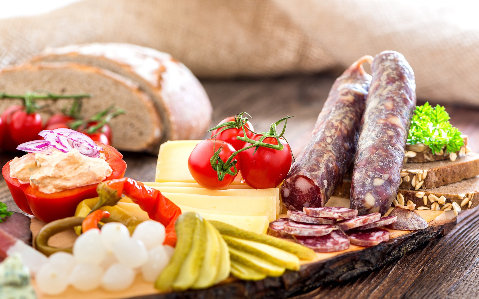 Колбаса на столе с огурцами, помидорами и перцем