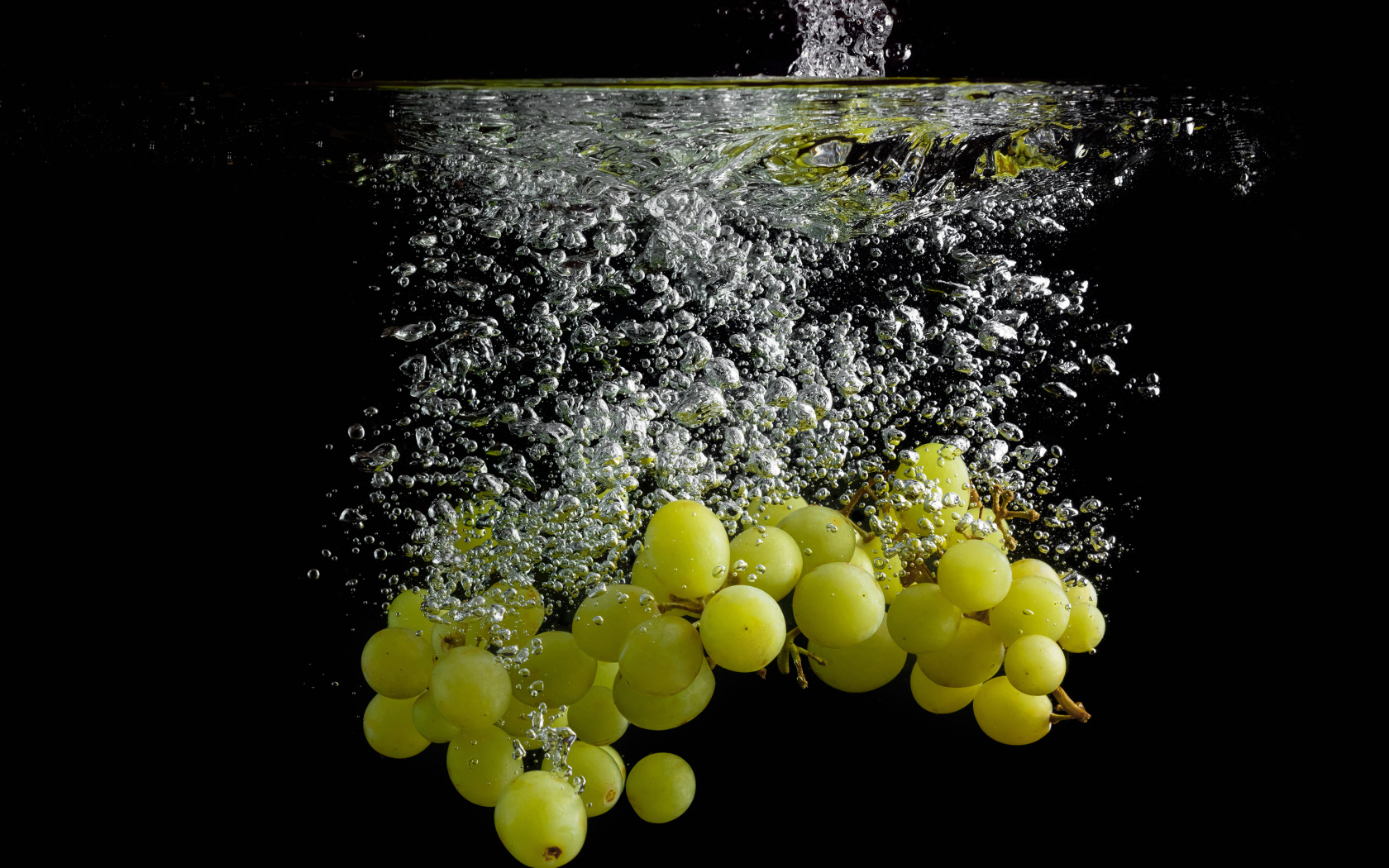 Ягоды белого винограда в воде на черном фоне
