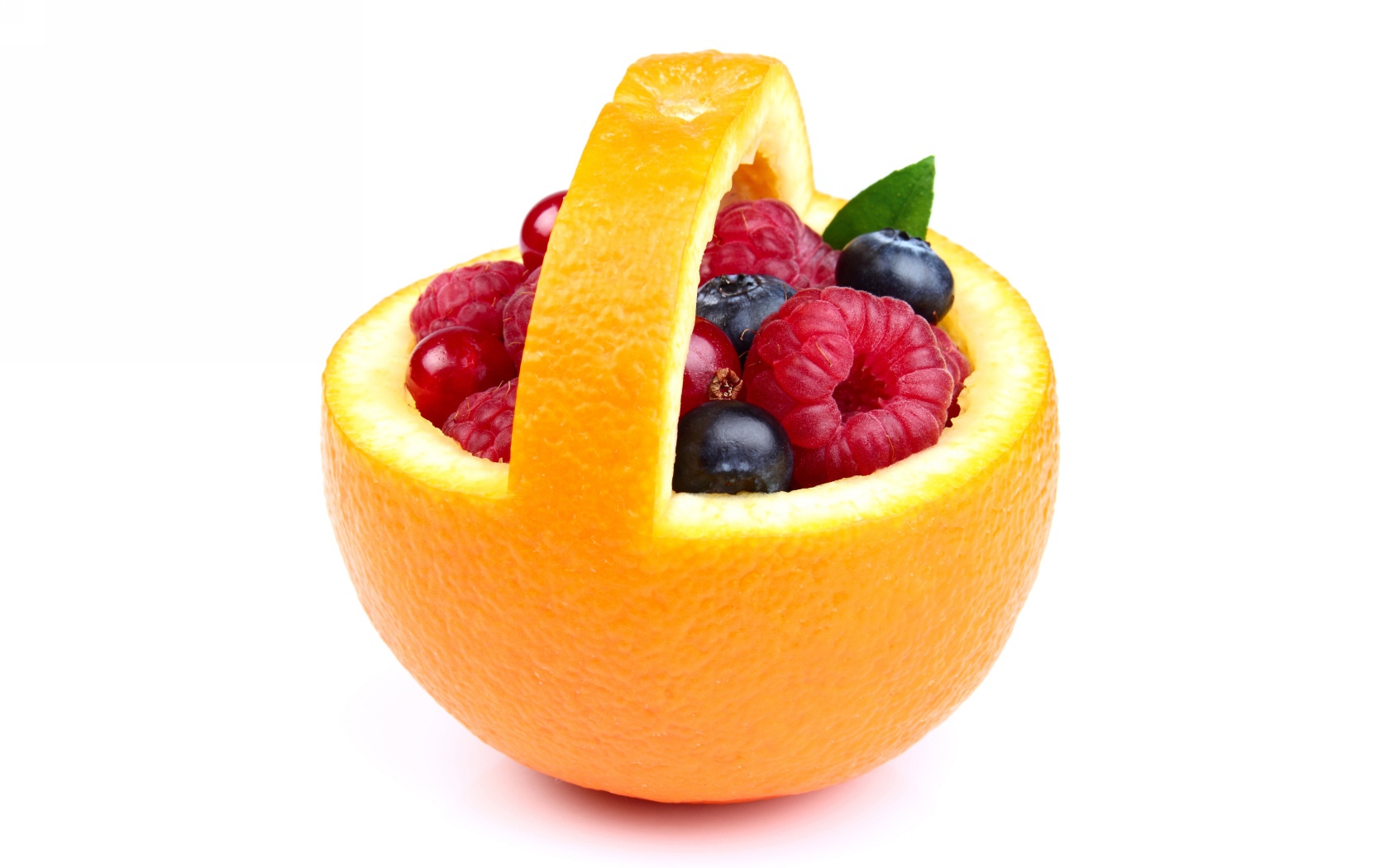 Свежие ягоды в кожуре апельсина на белом фоне