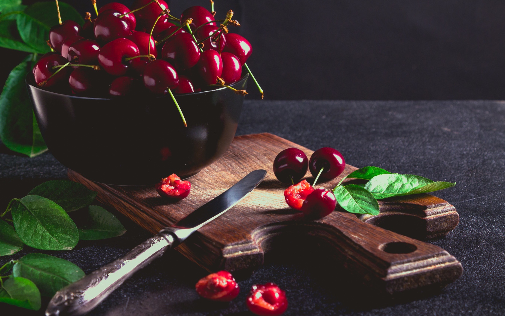 Спелые красные черешни на разделочной доске на столе 