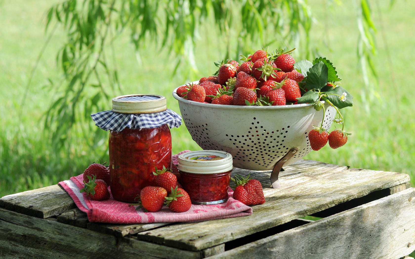 Спелая красная клубника с вареньем стоят на ящике 