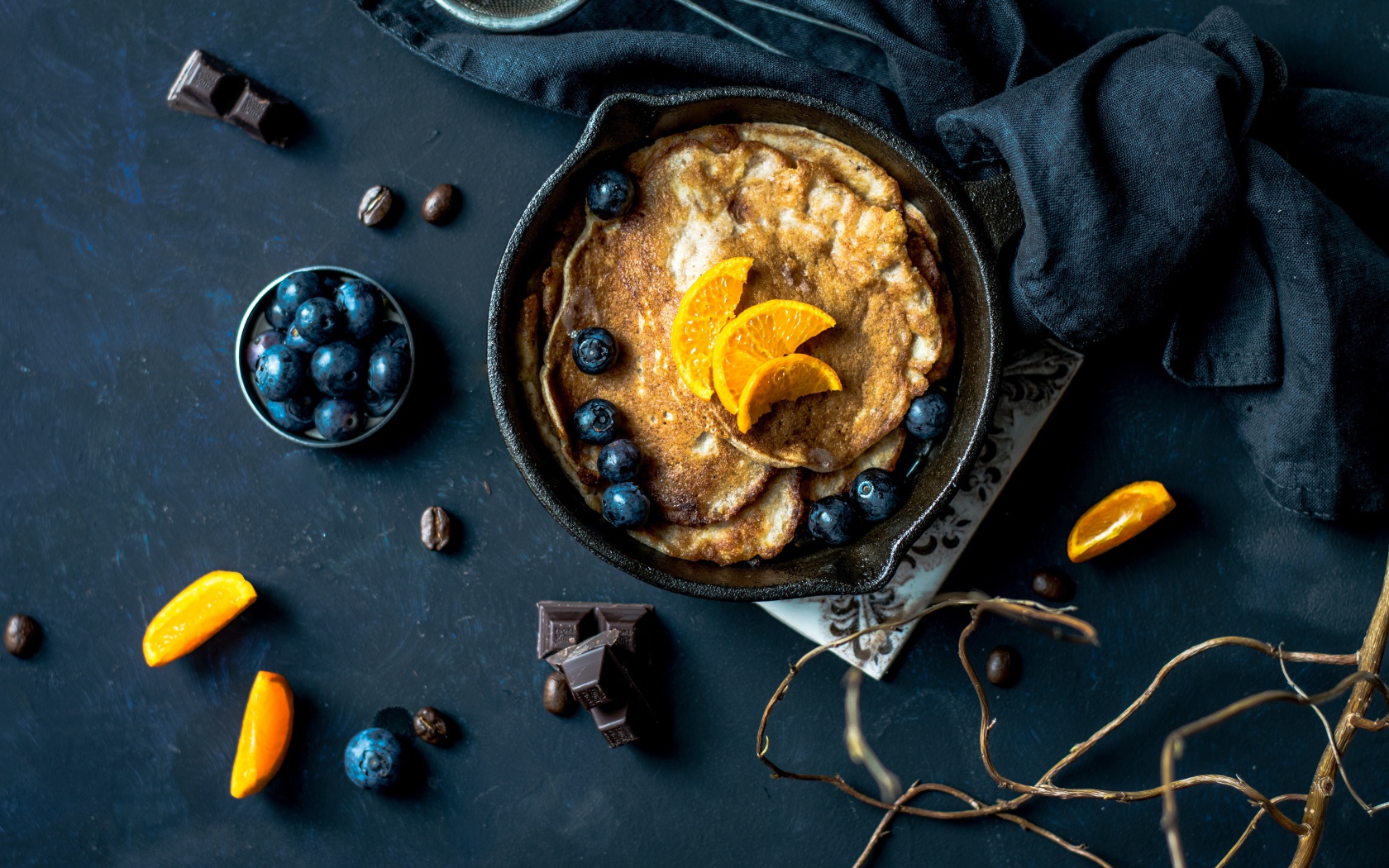 Блины с ягодами черники и апельсинами на столе 