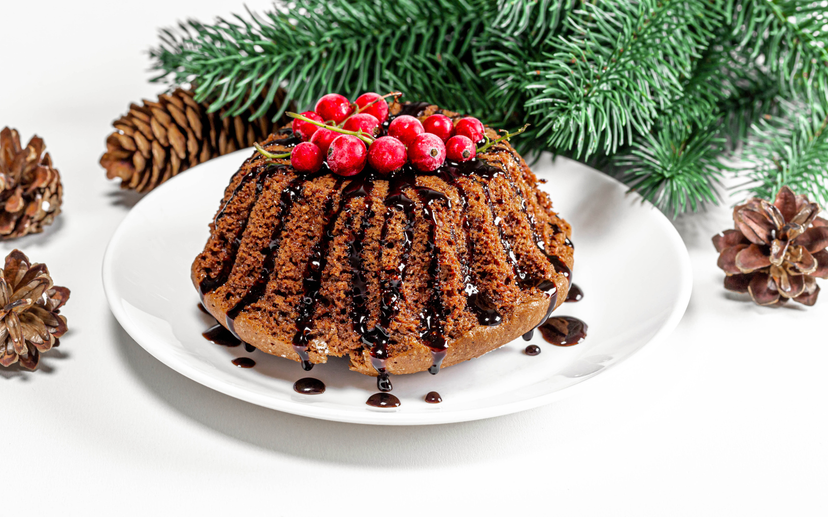 Вкусный кекс с шоколадом и красной смородиной на столе с еловой веткой и шишками