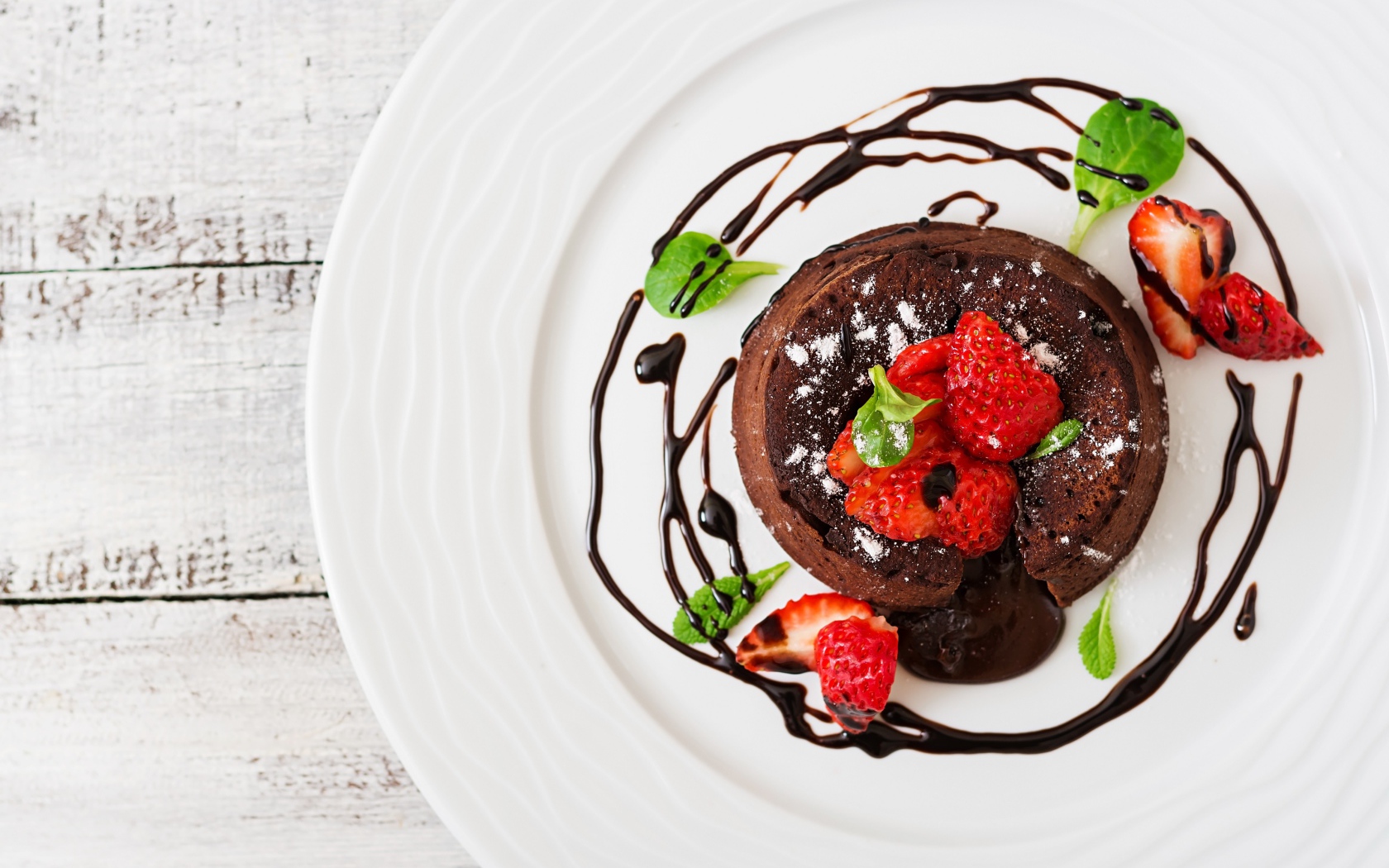 Вкусный десерт на белой тарелке с клубникой и шоколадом