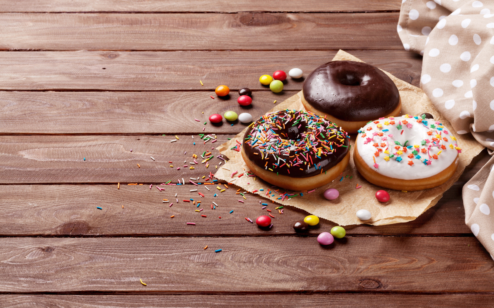 Пончики с глазурью на столе с конфетами на деревянном столе