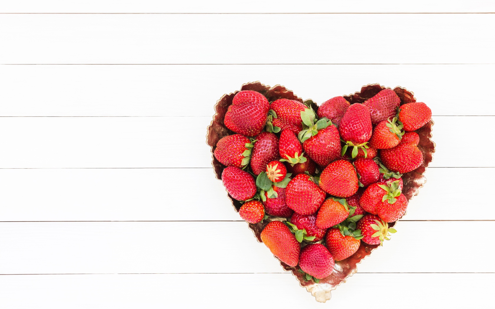 Пирожное в форме сердца с клубникой на белом фоне