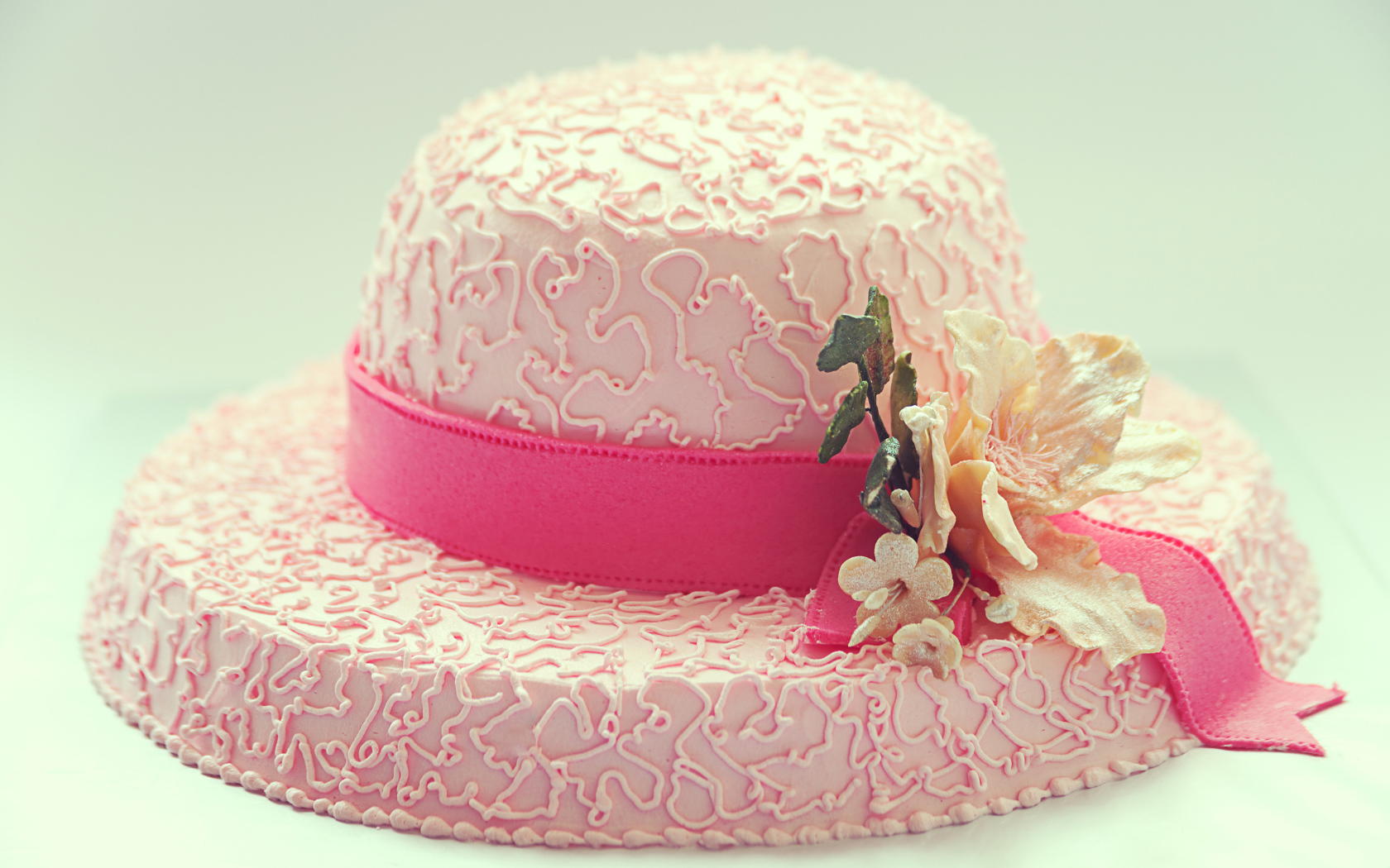 Розовый торт в виде шляпы на столе 