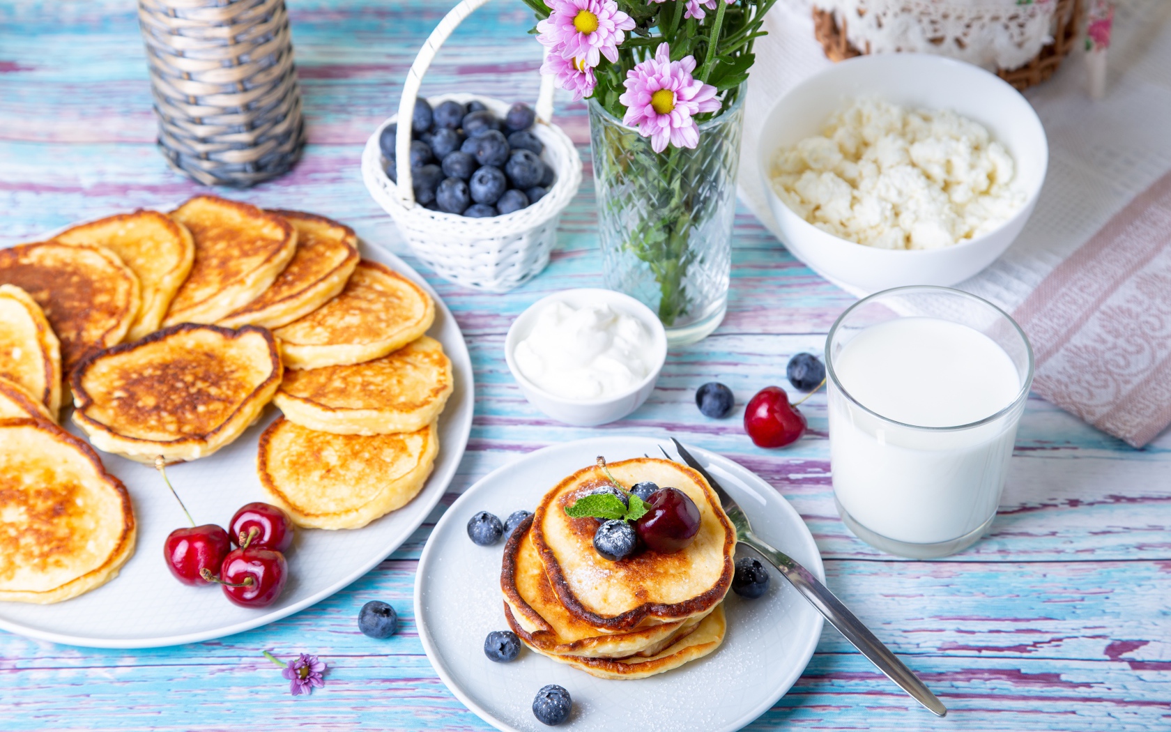 Вкусные оладьи на столе с ягодами черники, творогом и молоком