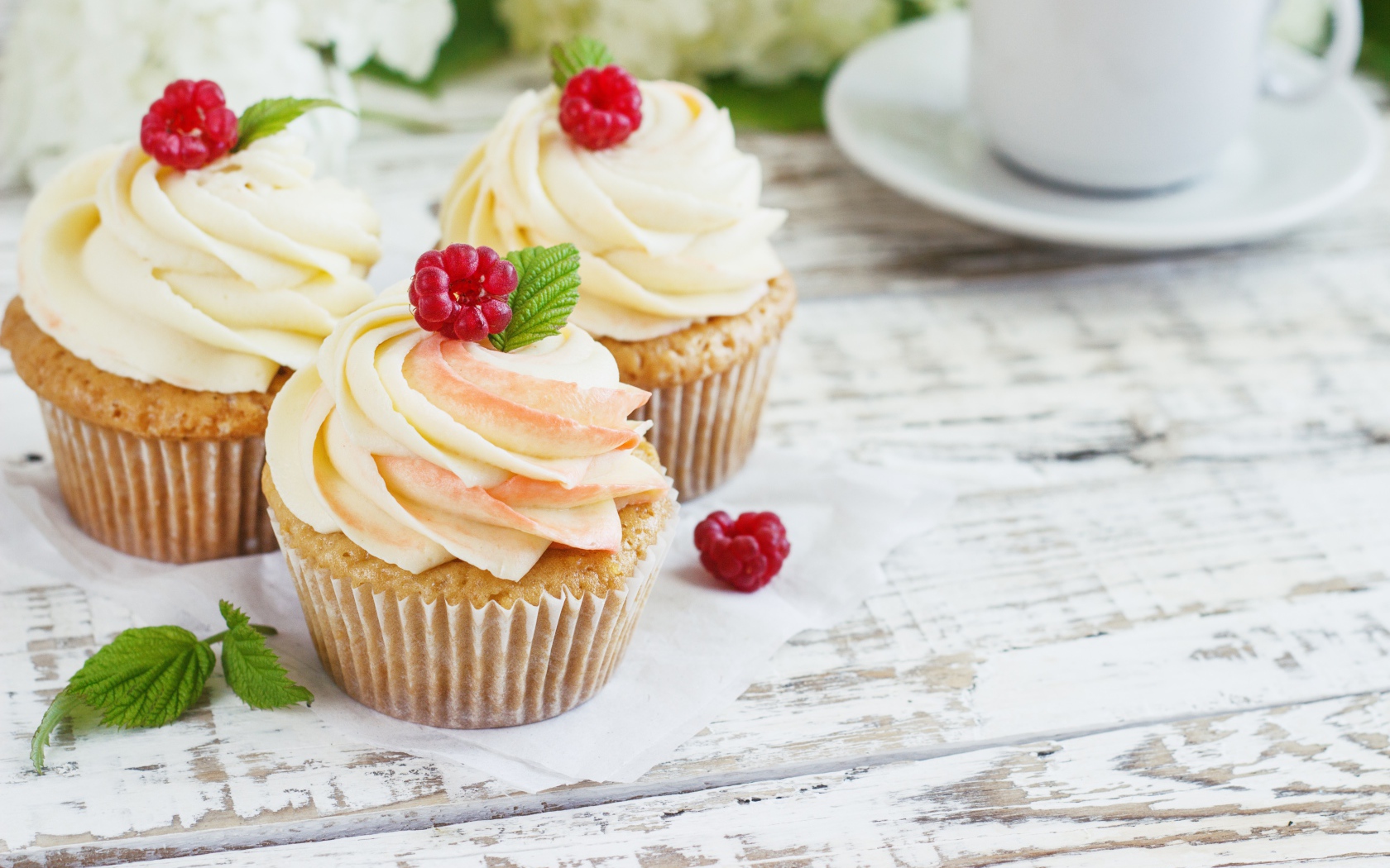 Три кекса с кремом на столе с чашкой кофе