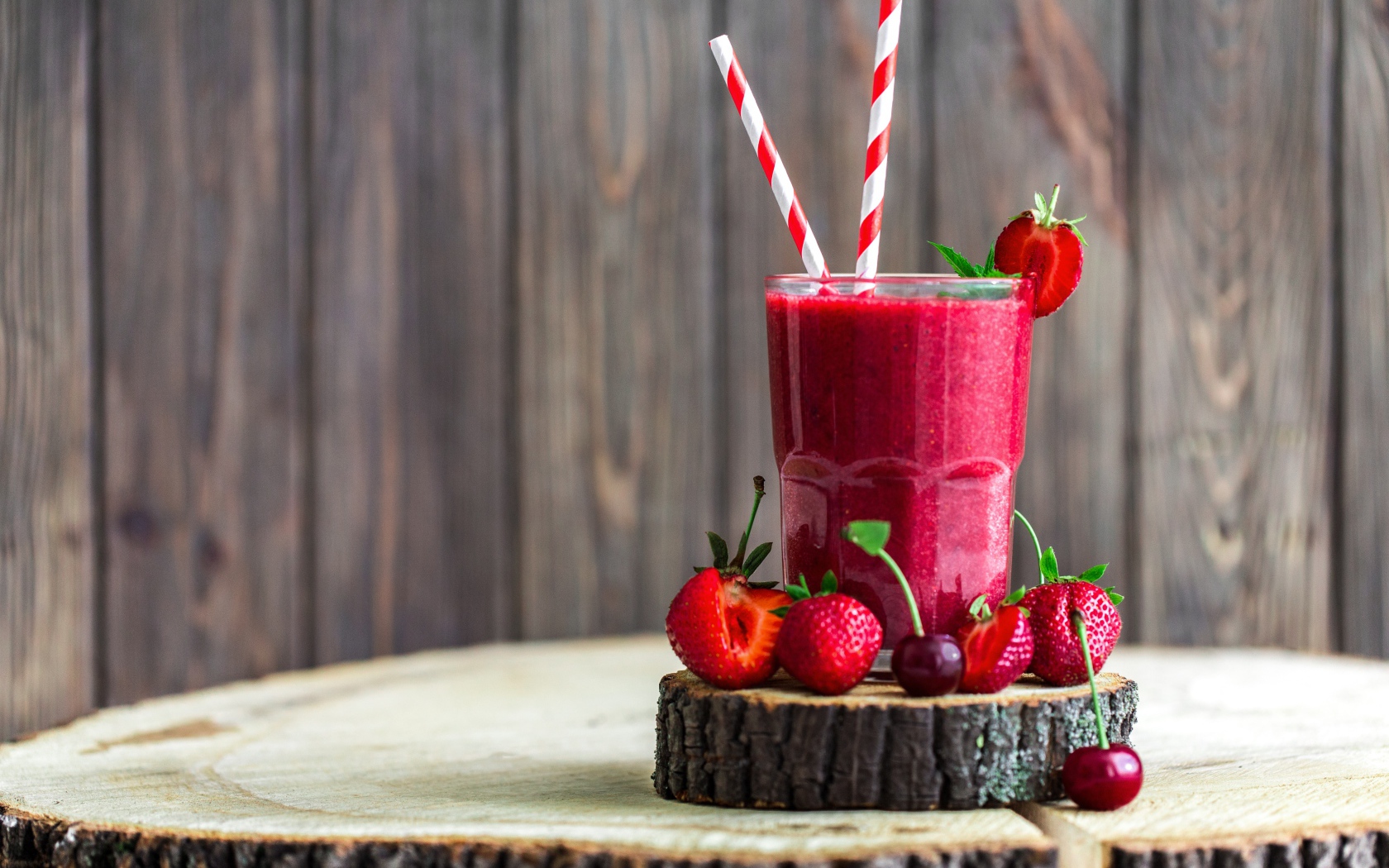 Стакан ягодного смузи на столе с клубникой и вишней