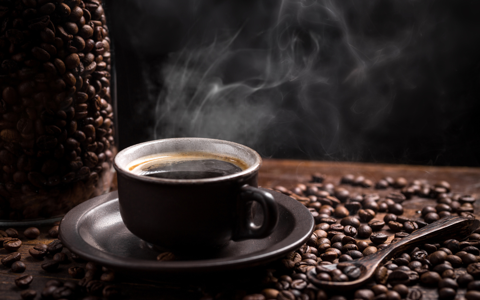 Чашка горячего ароматного кофе на столе с зернами и ложкой