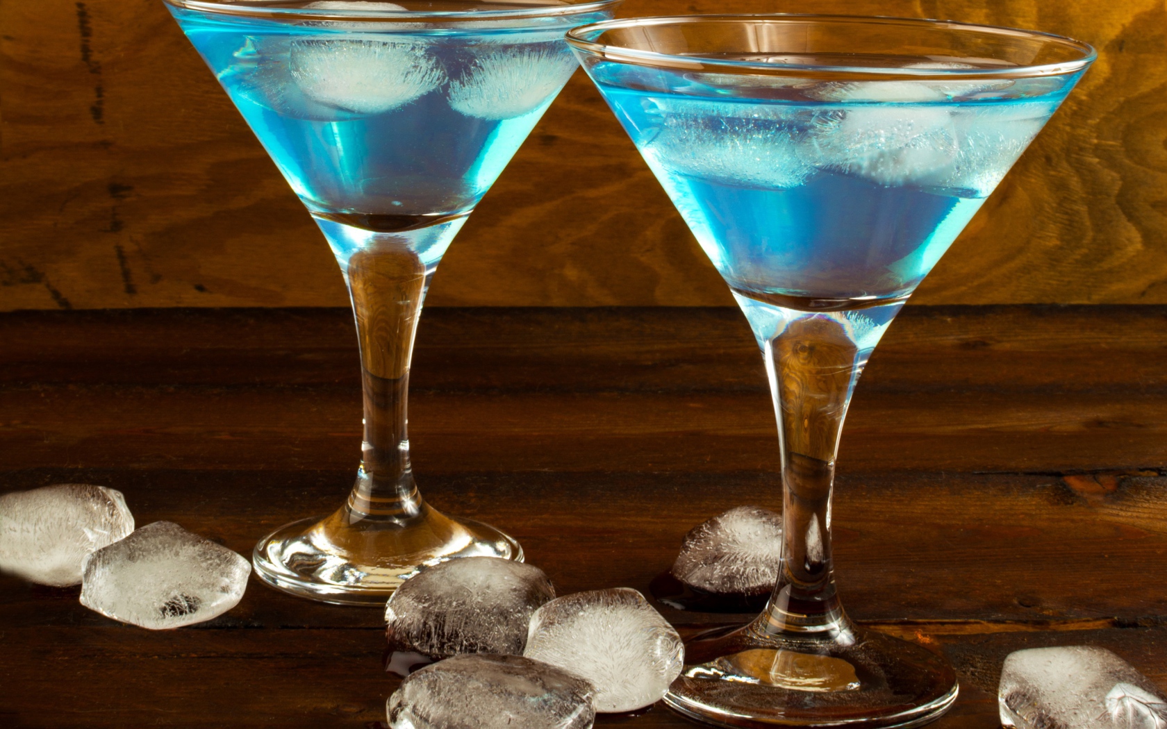 Два бокала коктейля на столе с кусочками льда