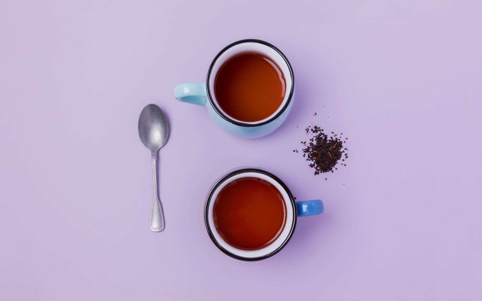Две железные чашки чая на сиреневом фоне с ложкой