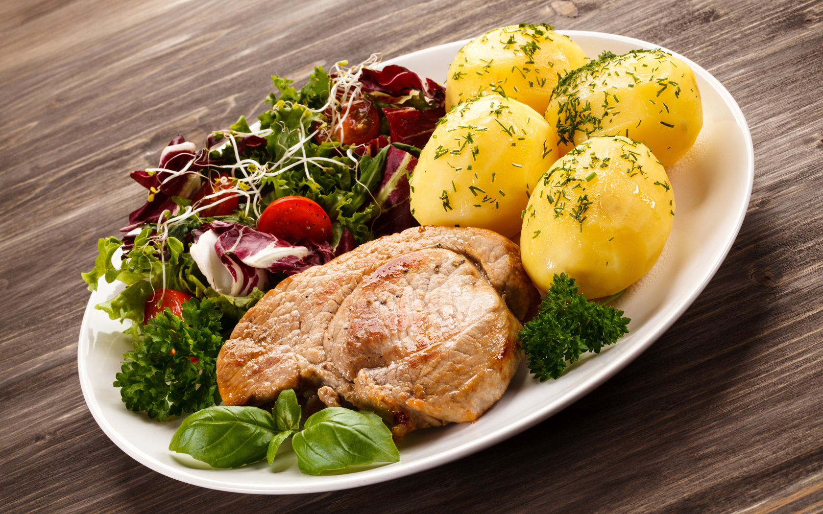 Кусок мяса на тарелке с картофелем и салатом