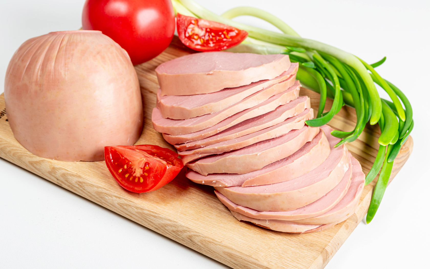 Вареная колбаса на доске с луком и помидором