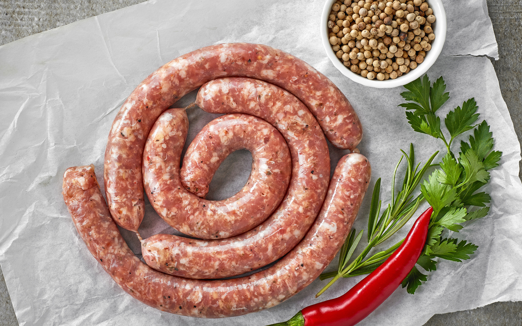 Домашняя колбаса на столе с зеленью и перцем