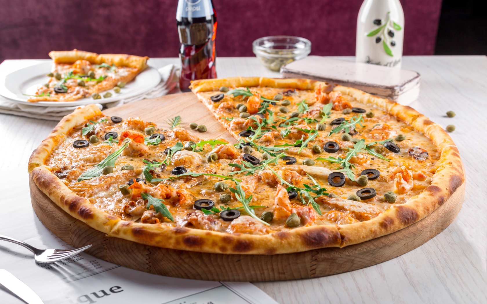 Большая аппетитная пицца с маслинами на столе в кафе