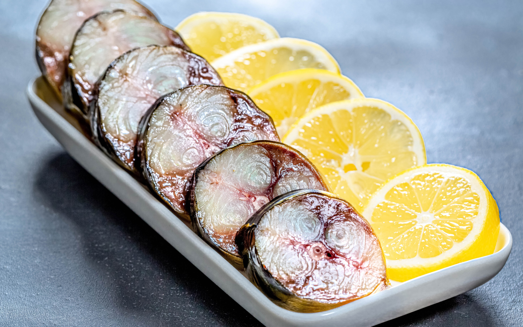 Куски скумбрии в тарелке с кусочками лимона 