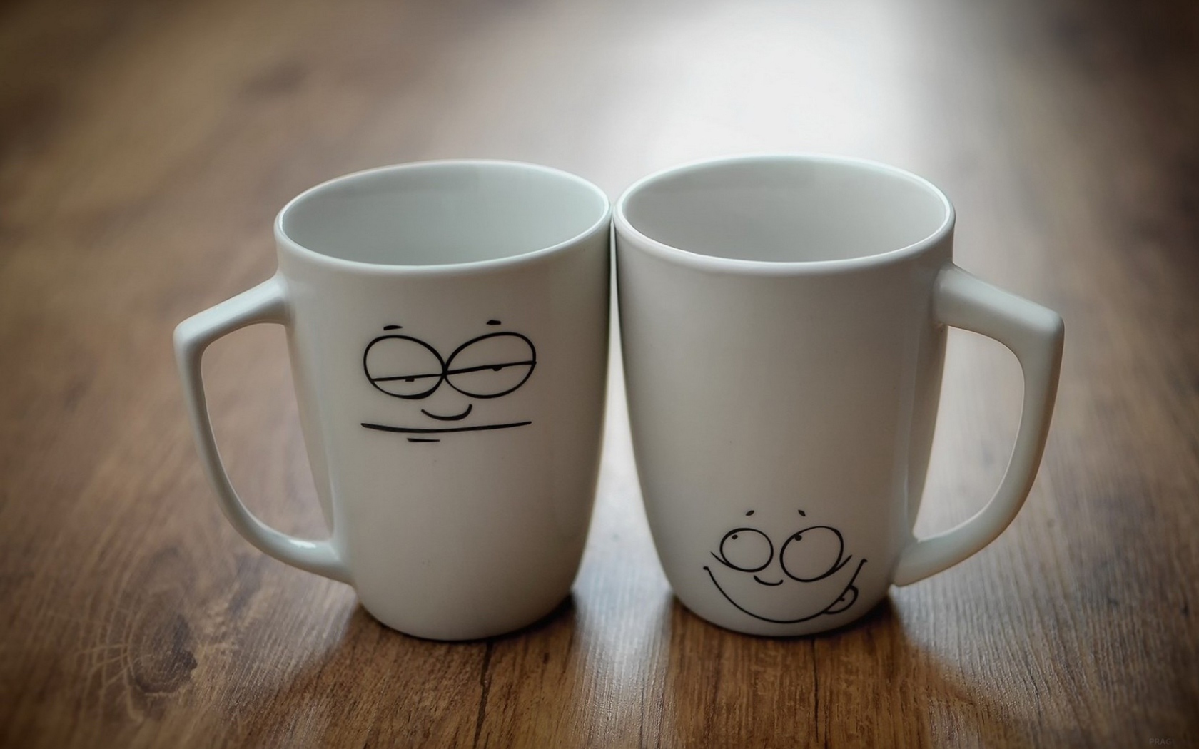 Две белые кружки с рисунками на столе 