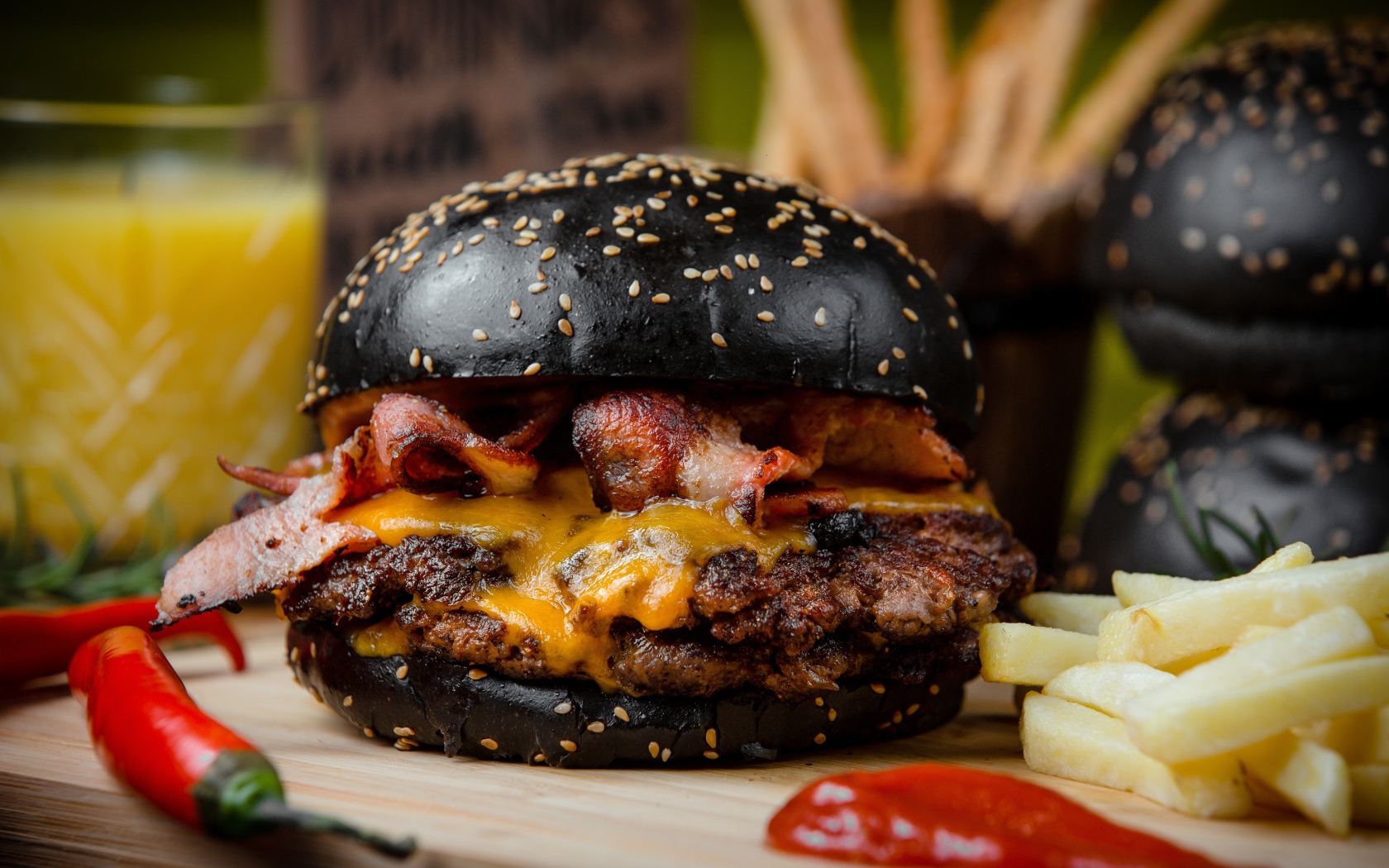 Гамбургер с черной булкой на столе с картофелем фри и красным перцем