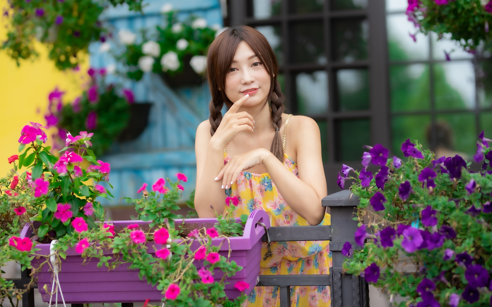 Милая азиатка стоит у кашпо с цветами петунии 