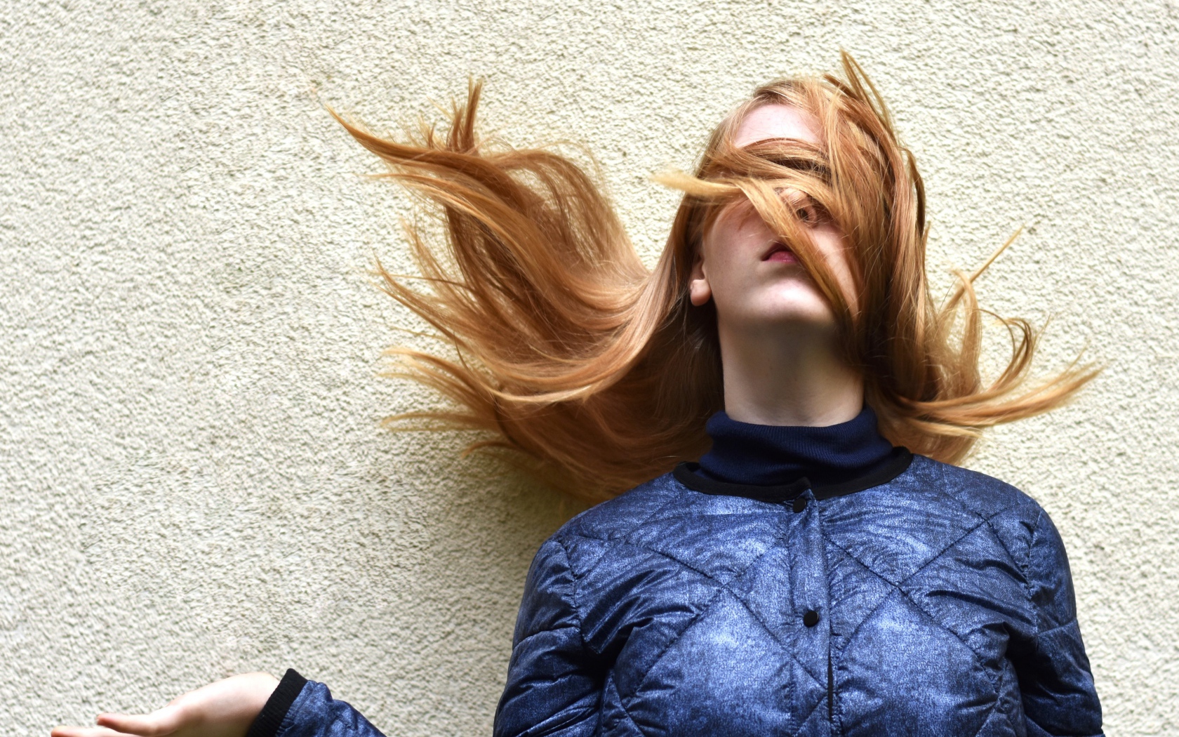 Девушка с волосами на лице стоит у стены