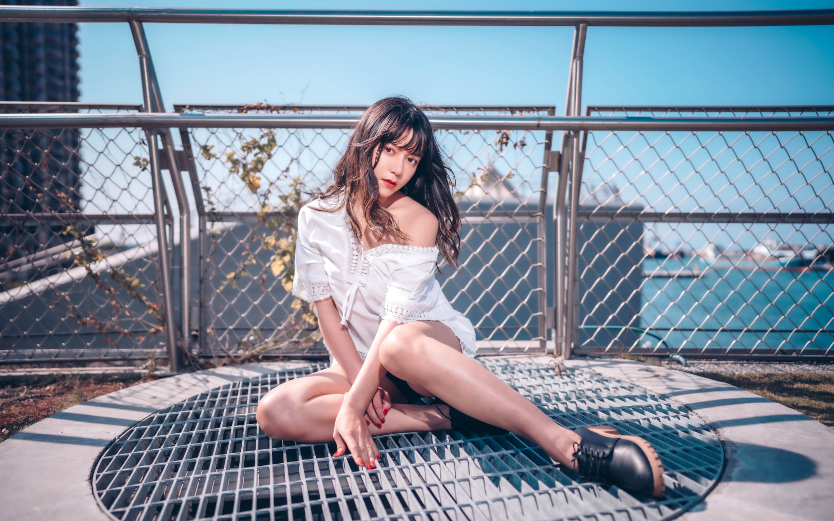 Девушка азиатка в белом наряде сидит на сетке