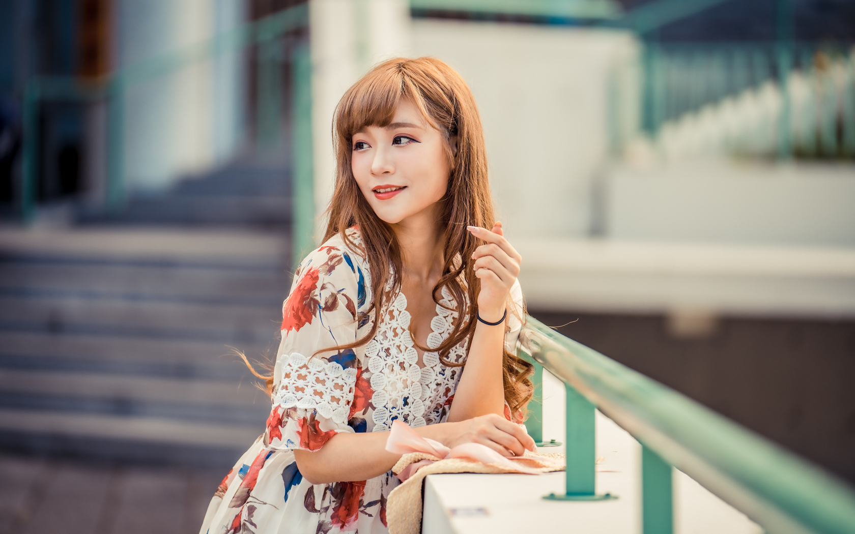 Красивая девушка азиатка стоит у перил 