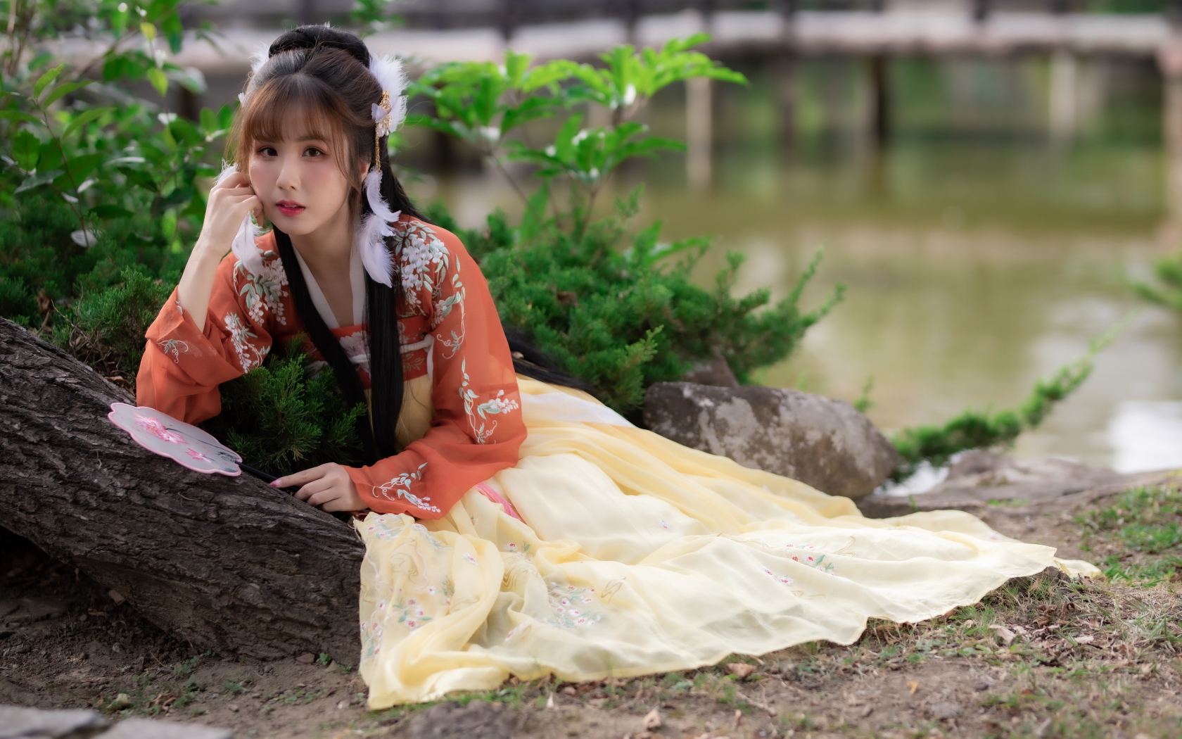 Красивая девушка азиатка сидит на земле у дерева 