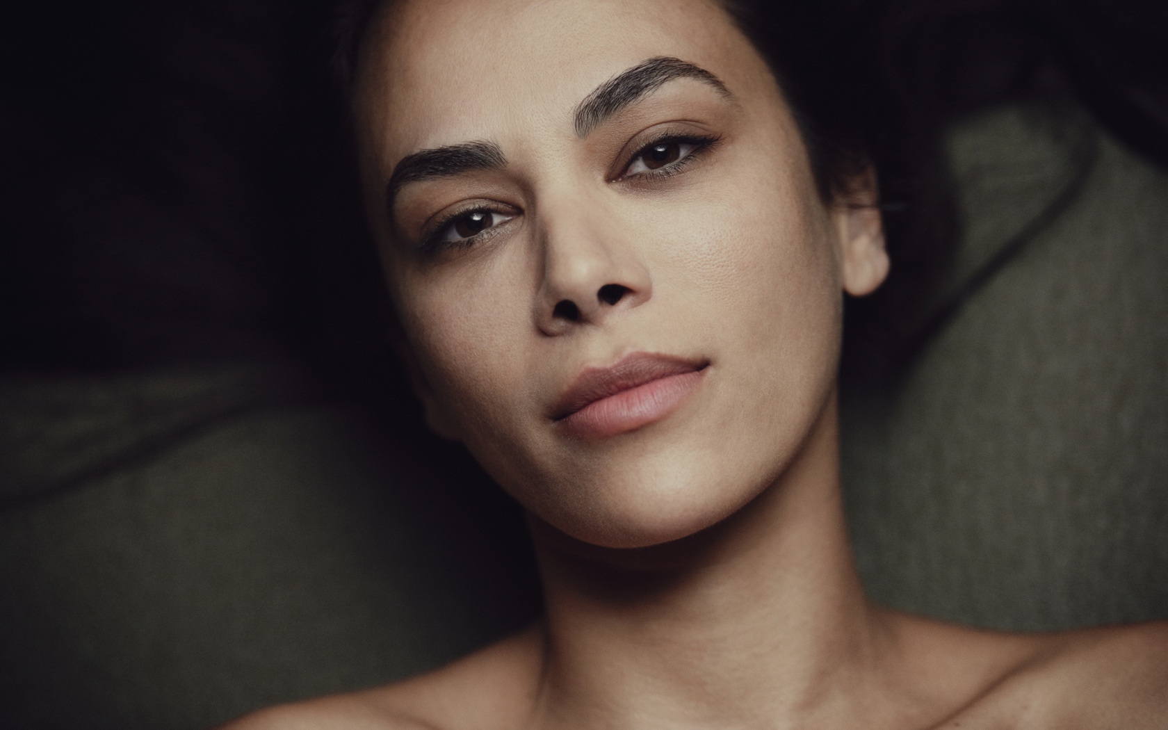 Красивая кареглазая девушка лежит на диване 