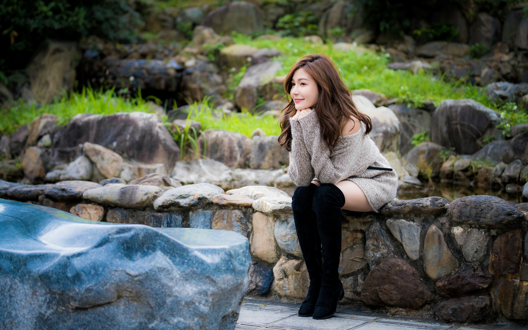 Красивая девушка в кофте сидит у пруда