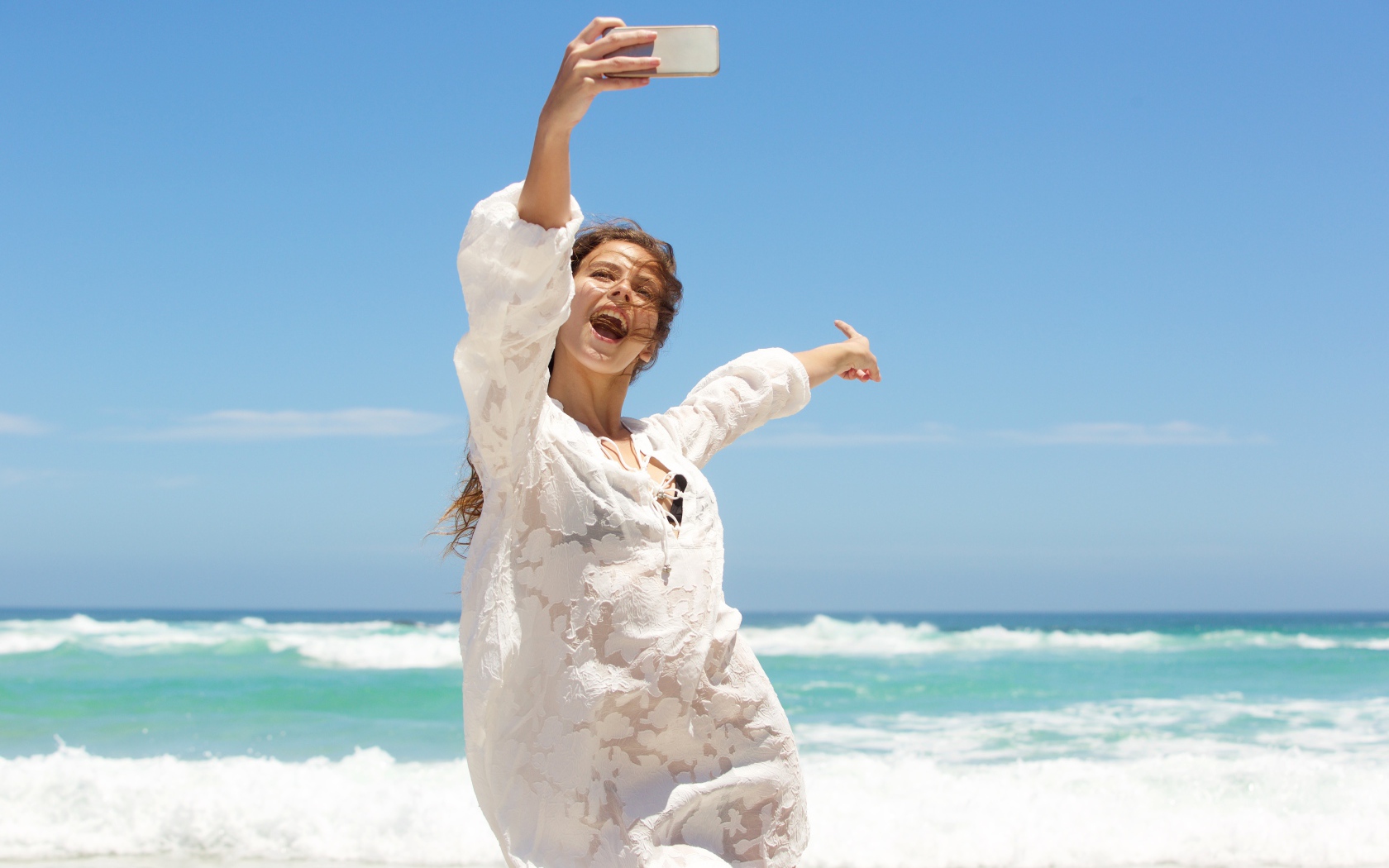 Красивая девушка в белом платье делает селфи на море 