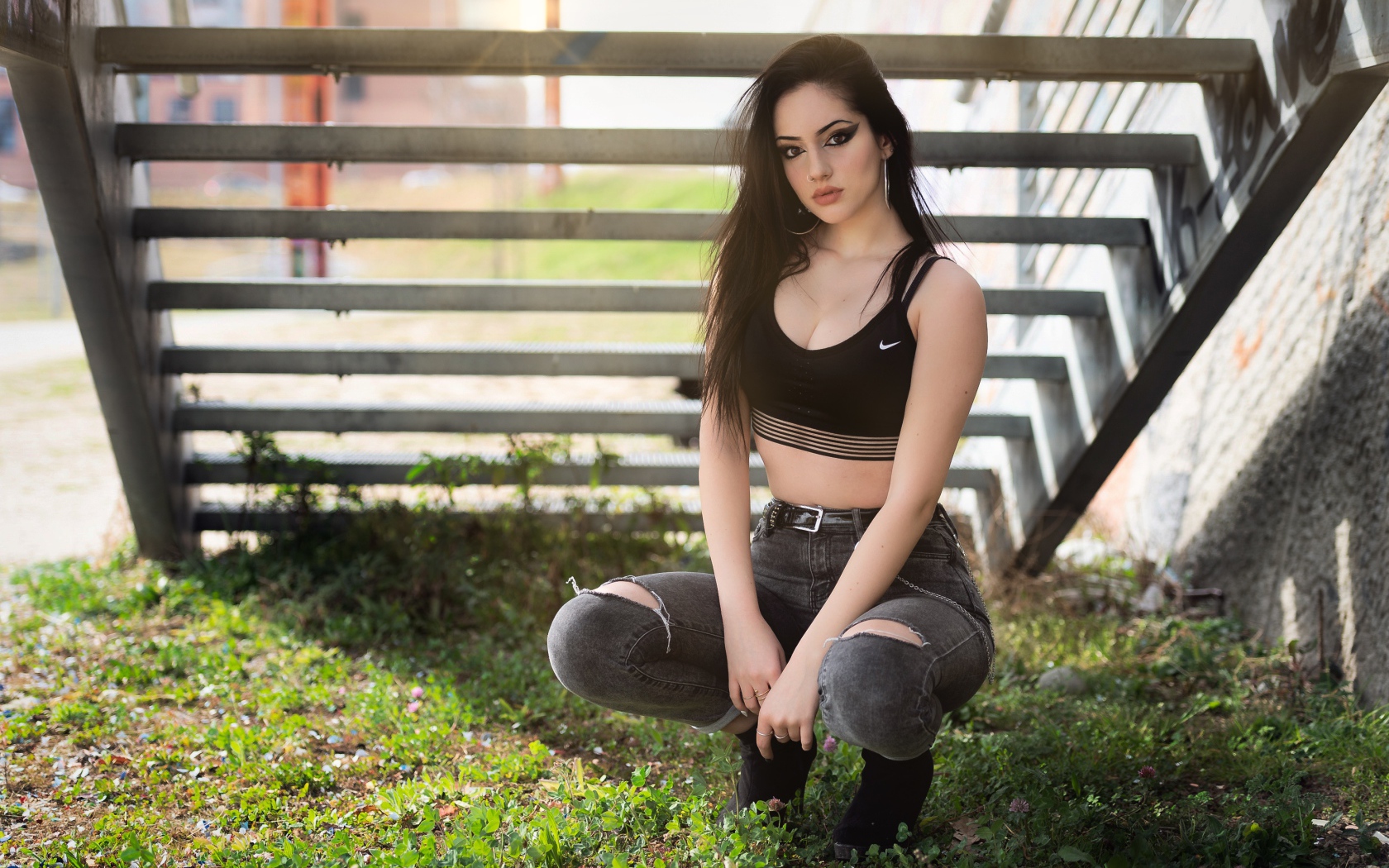 Красивая девушка сидит под лестницей 