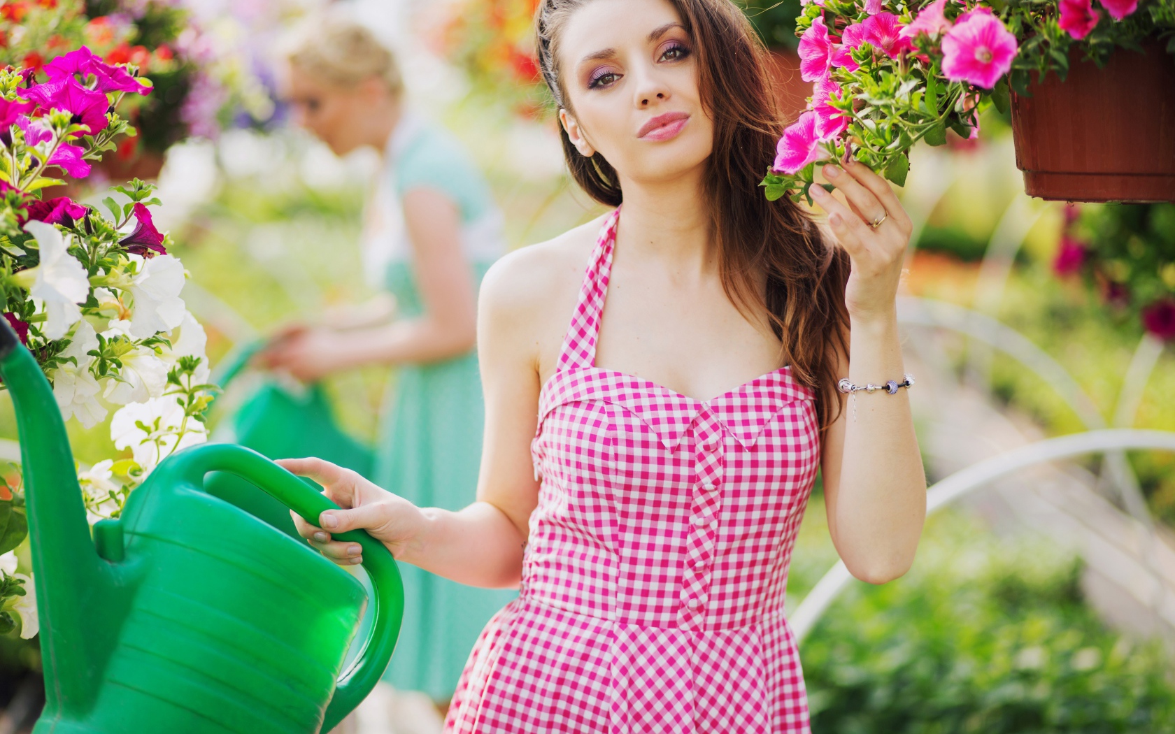 Красивая девушка с лейкой поливает цветы