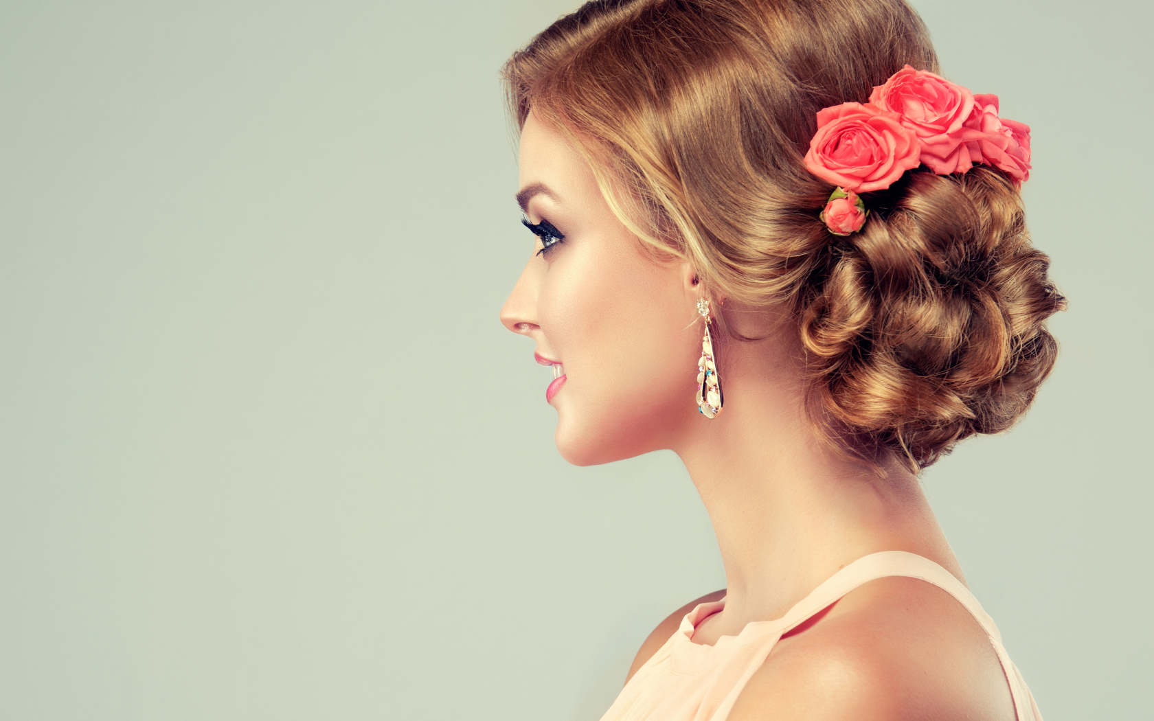 Красивая свадебная прическа у молодой девушки на сером фоне 