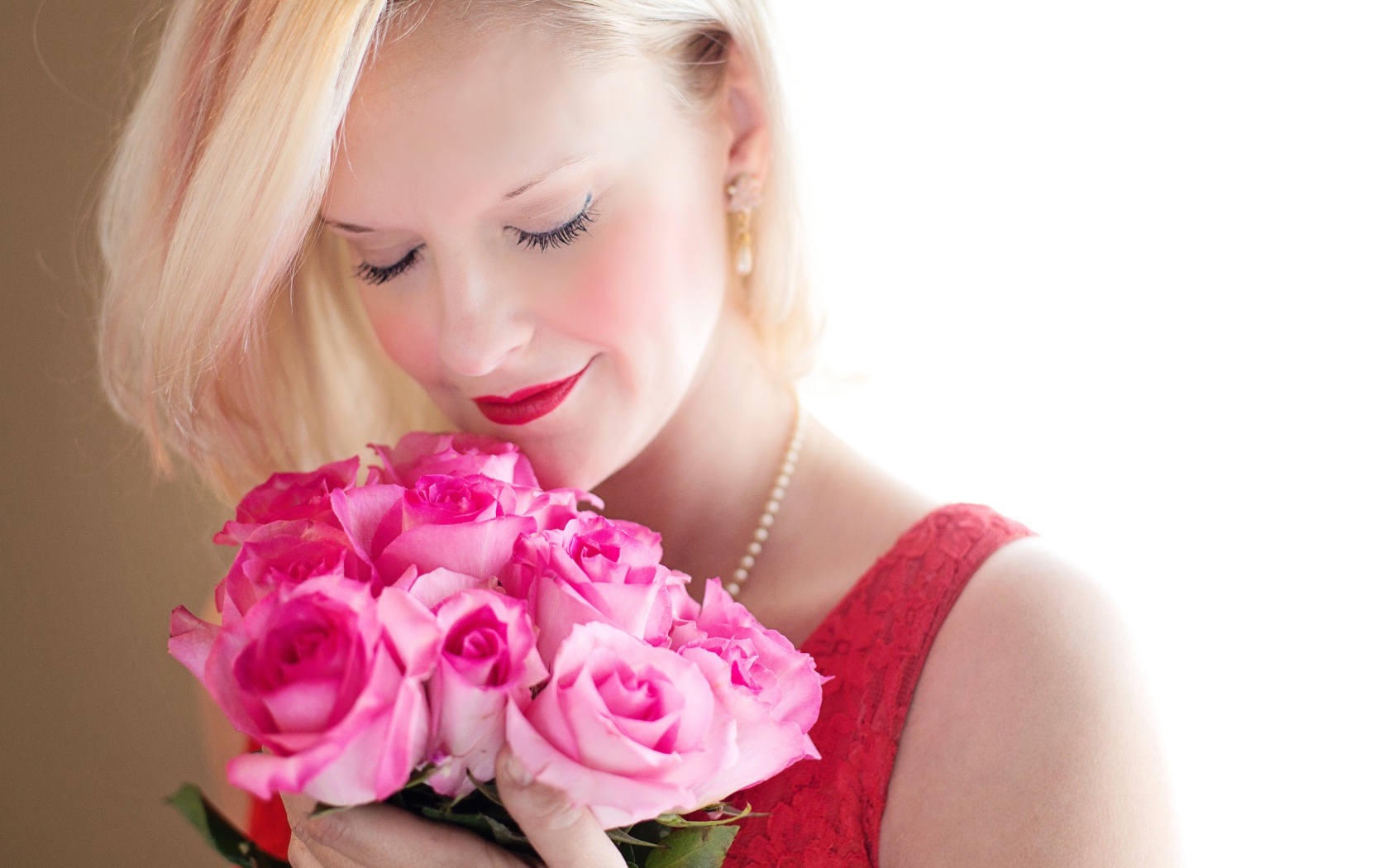 Блондинка с закрытыми глазами нюхает букет роз
