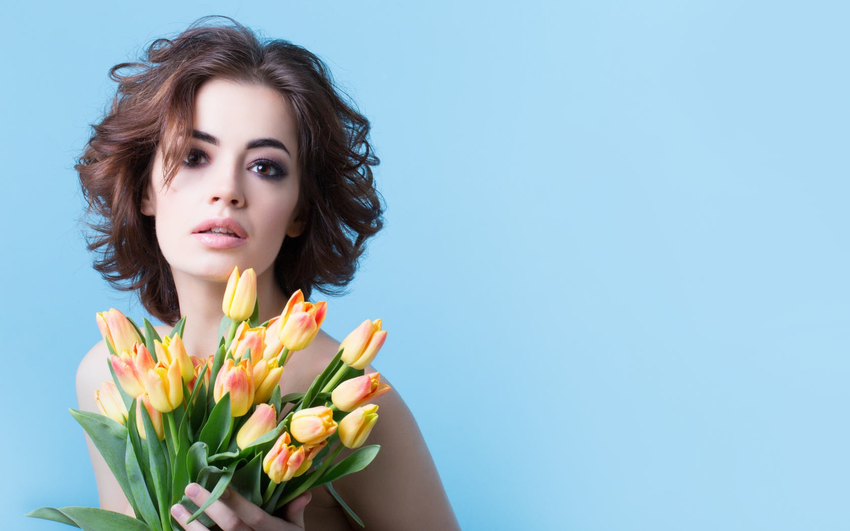 Кареглазая шатенка с букетом тюльпанов на голубом фоне